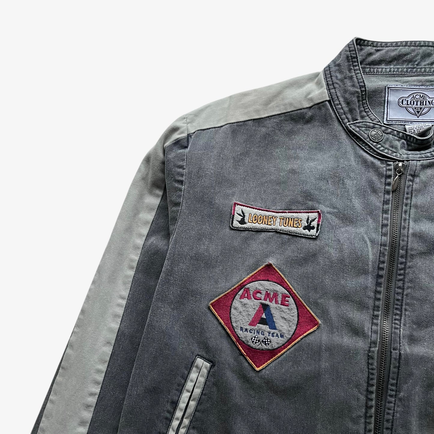 Close up of embroidered badges on the chest of a vintage 90s men's ACME Warner Bros Looney Tunes Bugs Bunny grey NASCAR jacket.
