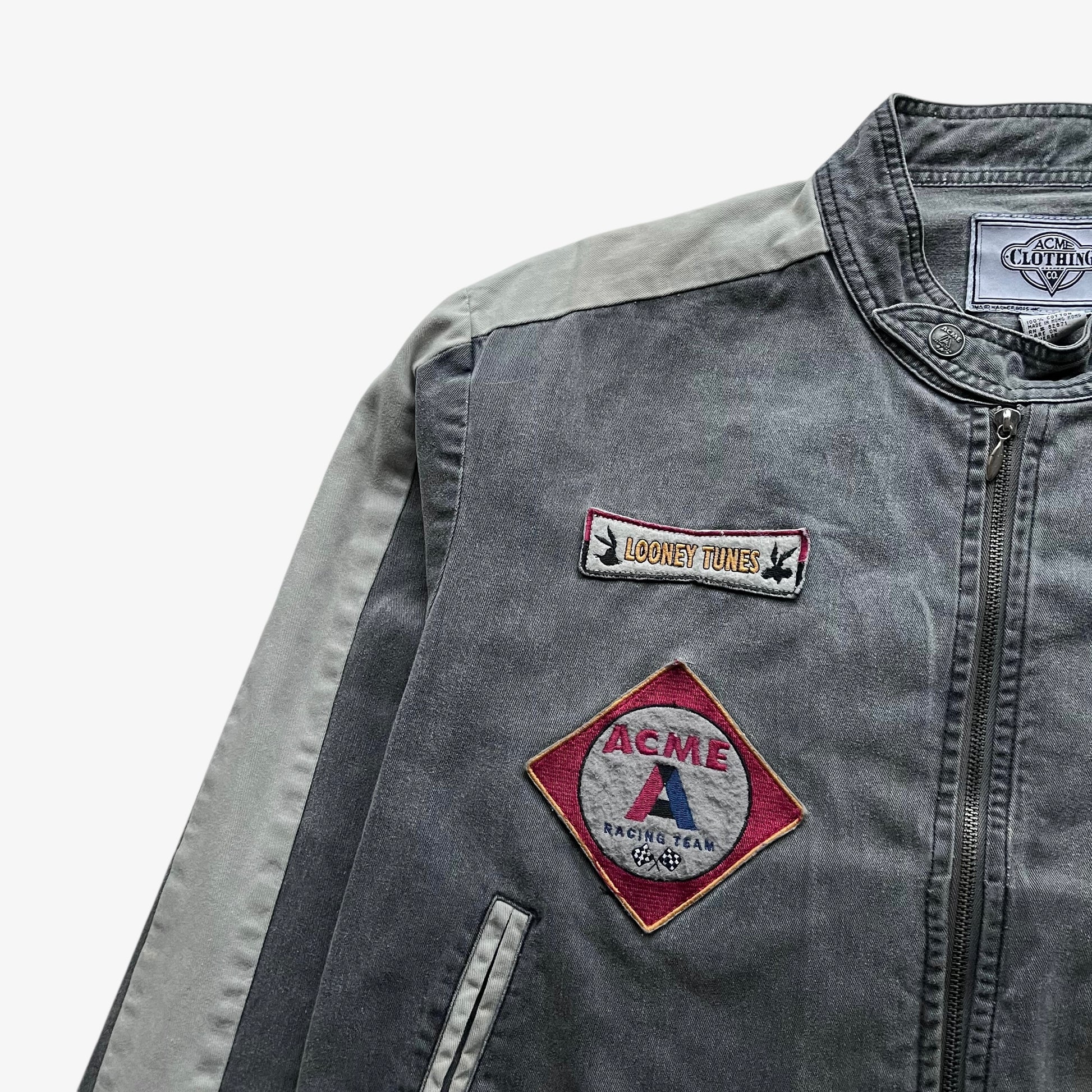 Close up of embroidered badges on the chest of a vintage 90s men's ACME Warner Bros Looney Tunes Bugs Bunny grey NASCAR jacket.
