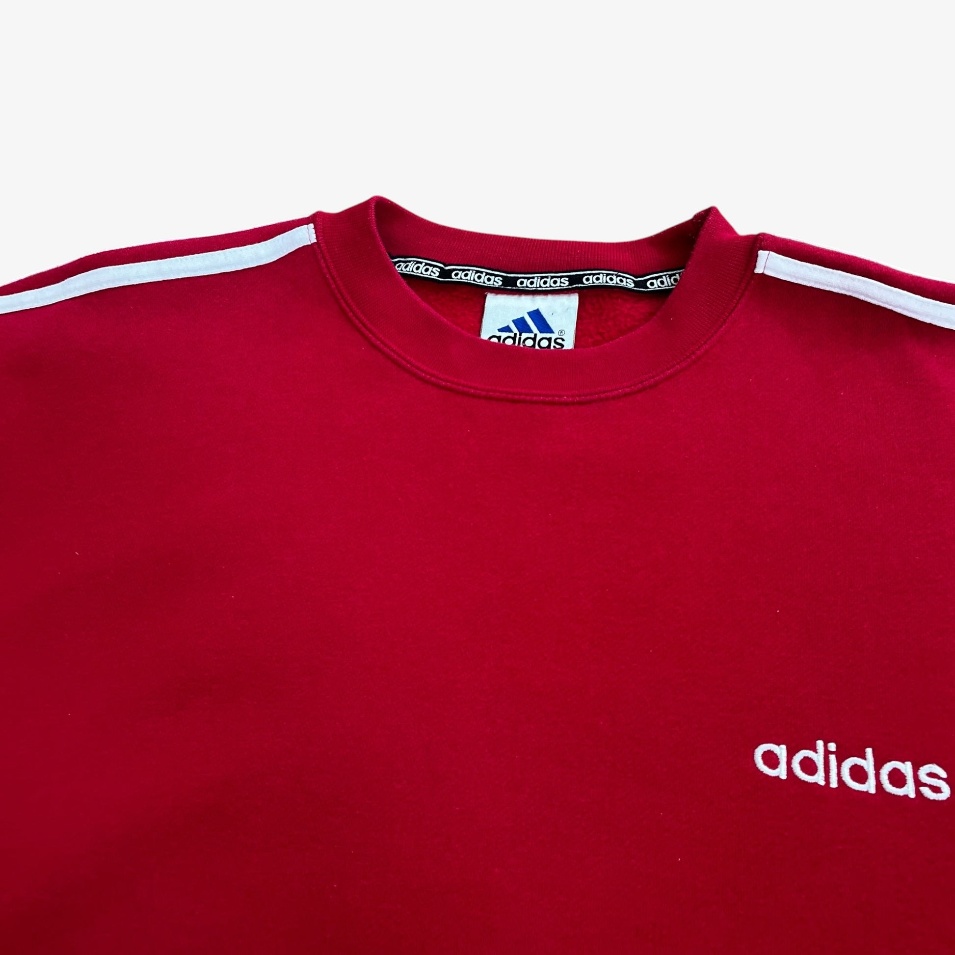 Close up of embroidered Adidas spell out on a red sweatshirt.