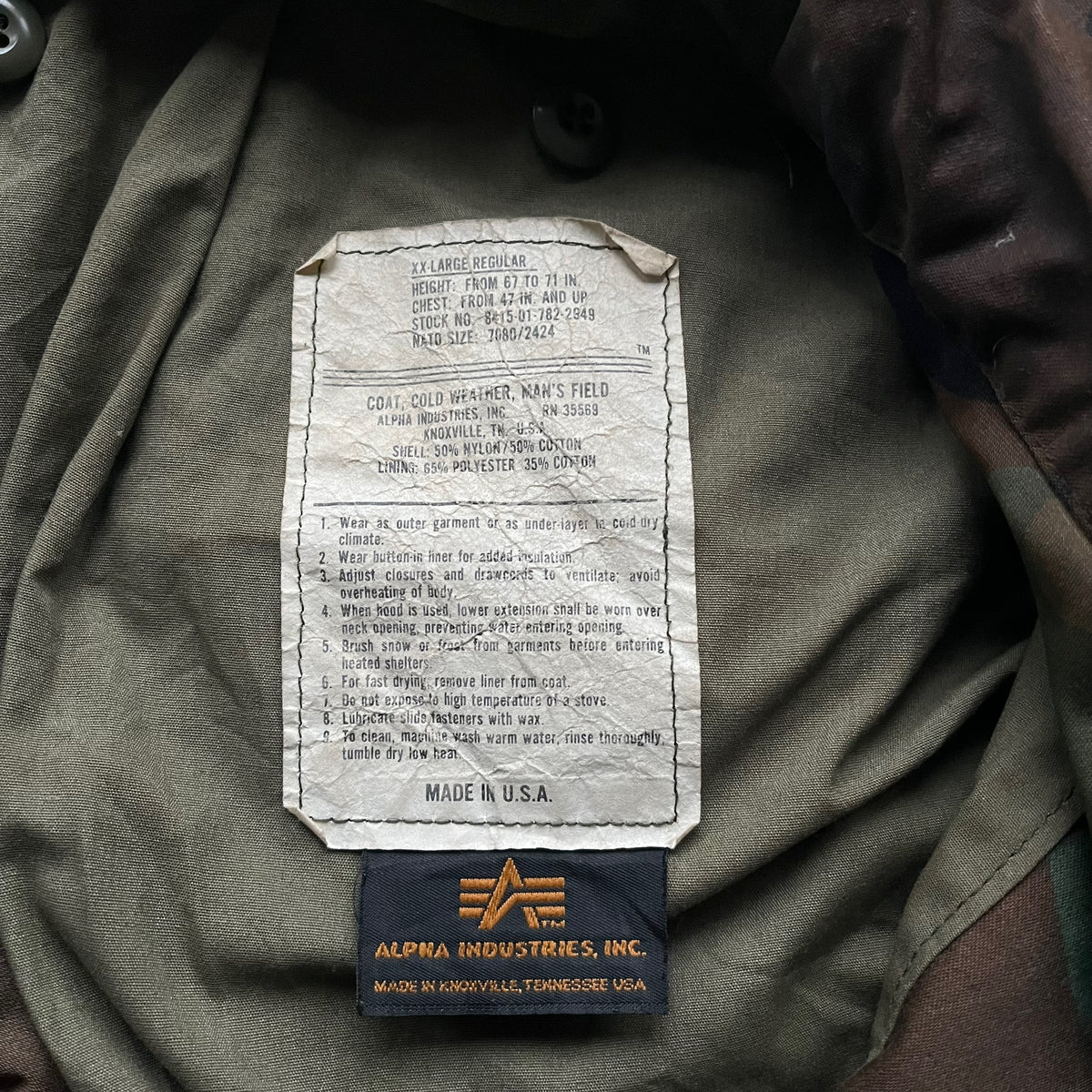 Alpha Industries cold weather label on vintage 90s men's M65 green camouflage field jacket.