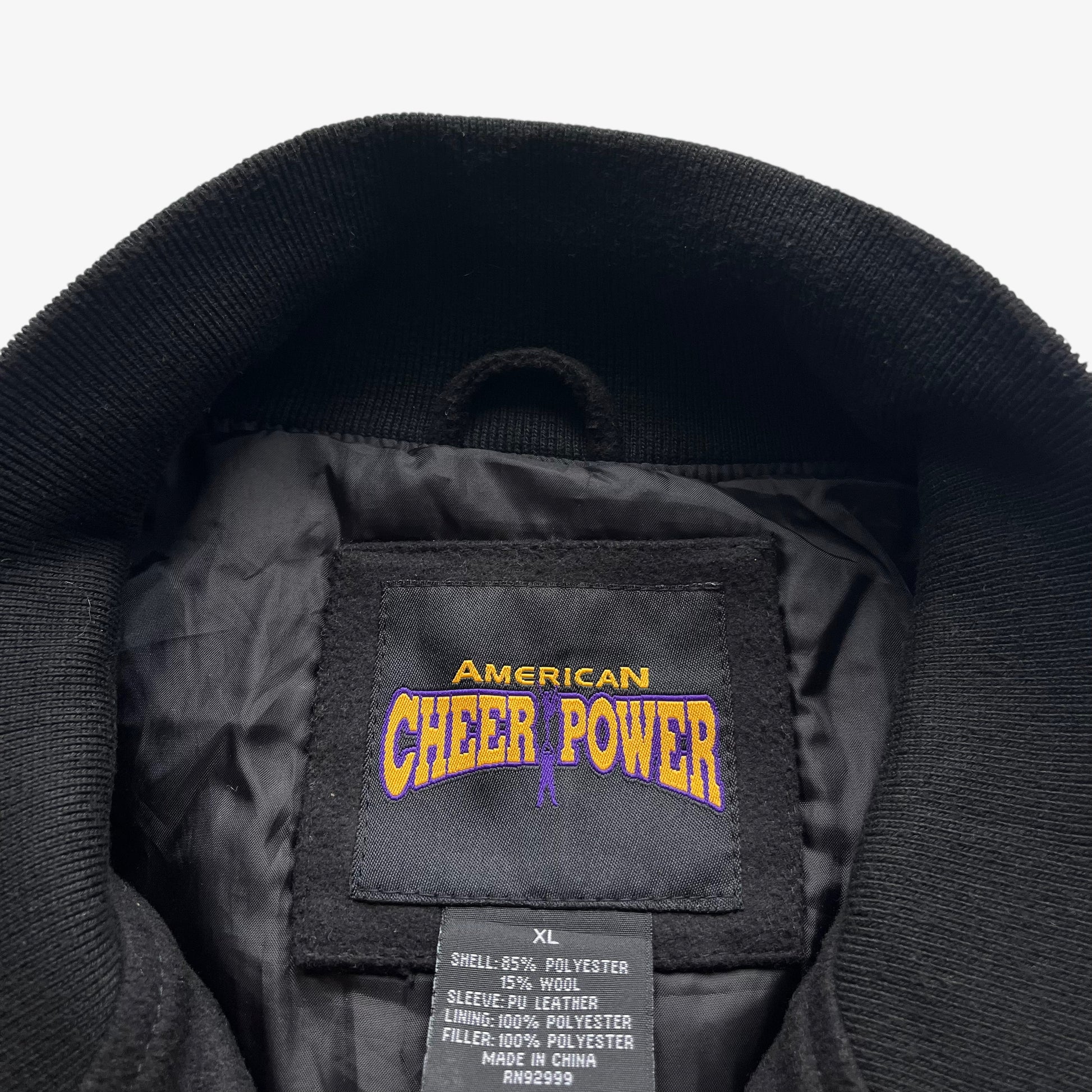 American Cheer Power stitched label inside of vintage 90s men's national champion wool blend black varsity jacket.