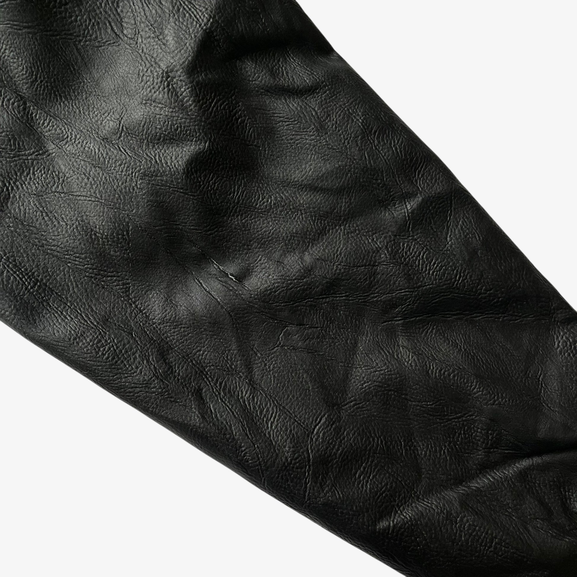 Patina on the sleeve of vintage 90s men's American Cheer Power national champion wool blend black varsity jacket.