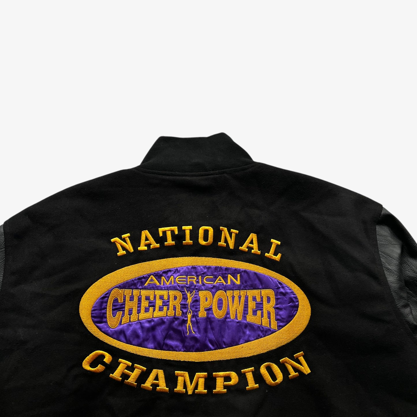 Back embroidered spell out of vintage 90s men's American Cheer Power national champion wool blend black varsity jacket.