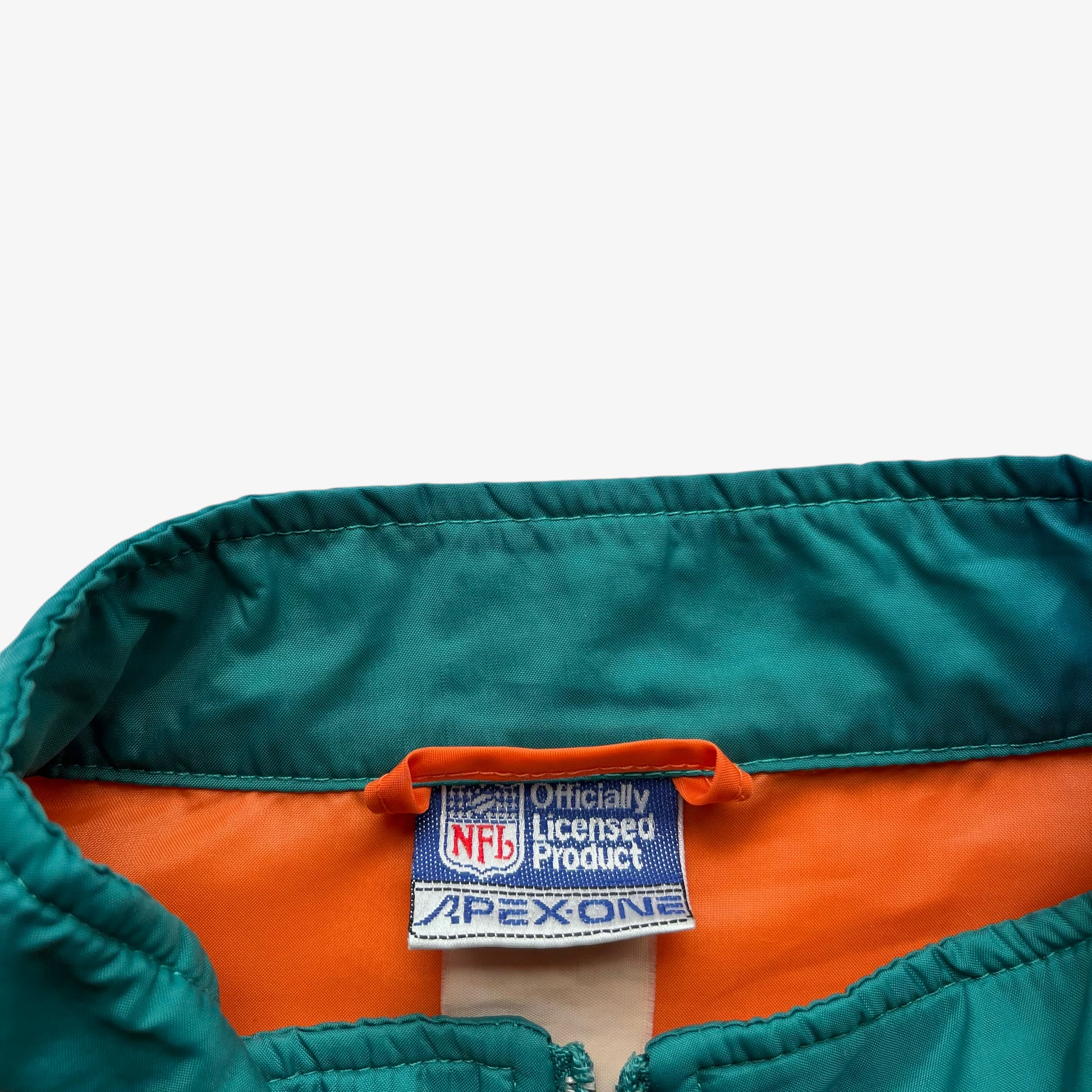Apex One label stitched inside of men's vintage 90s NFL Miami Dolphins jacket.