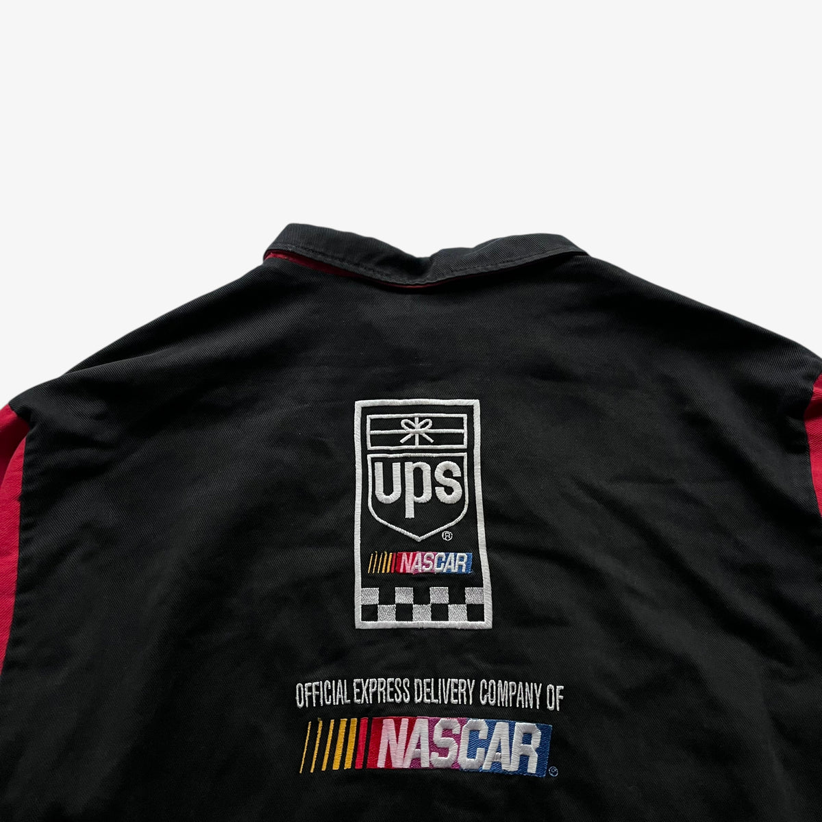 Back embroidered spell out of vintage 90s men's Ashley UPS black and red nascar jacket.