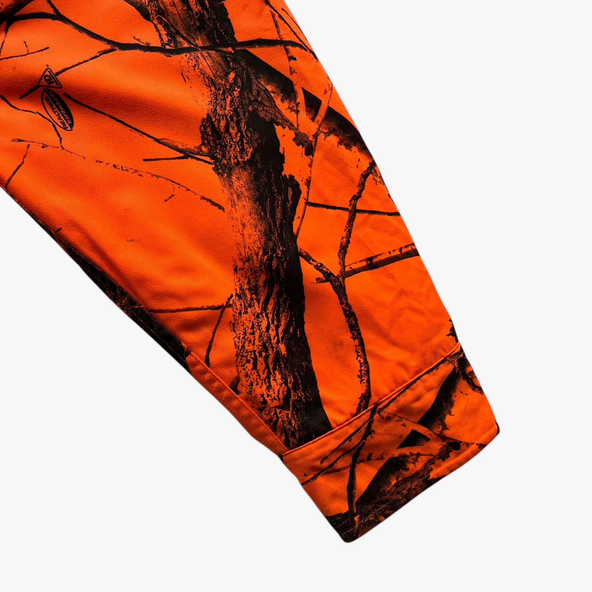 Patina on sleeve of vintage 90s men's Cabela's real tree hardwoods orange camouflage hunting jacket.