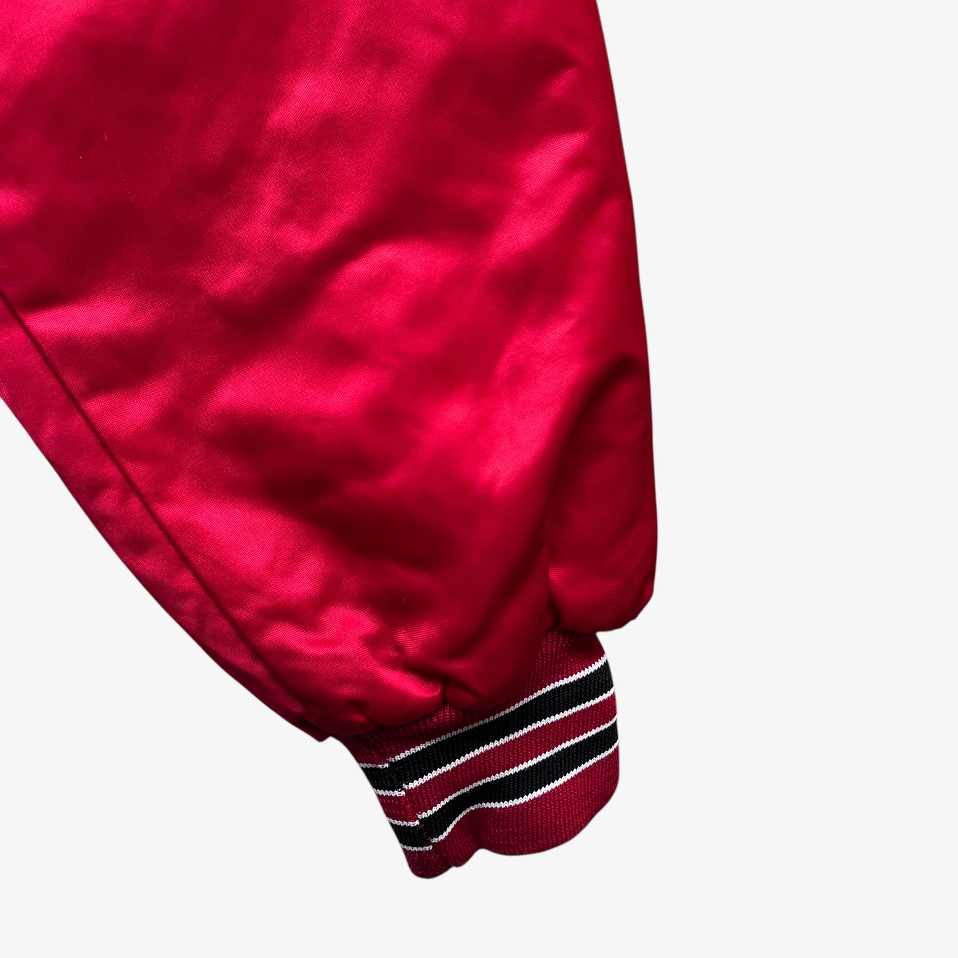 Cuff of men's vintage 90s Chalk Line NBA Chicago Bulls red varsity jacket with back embroidered spell out.