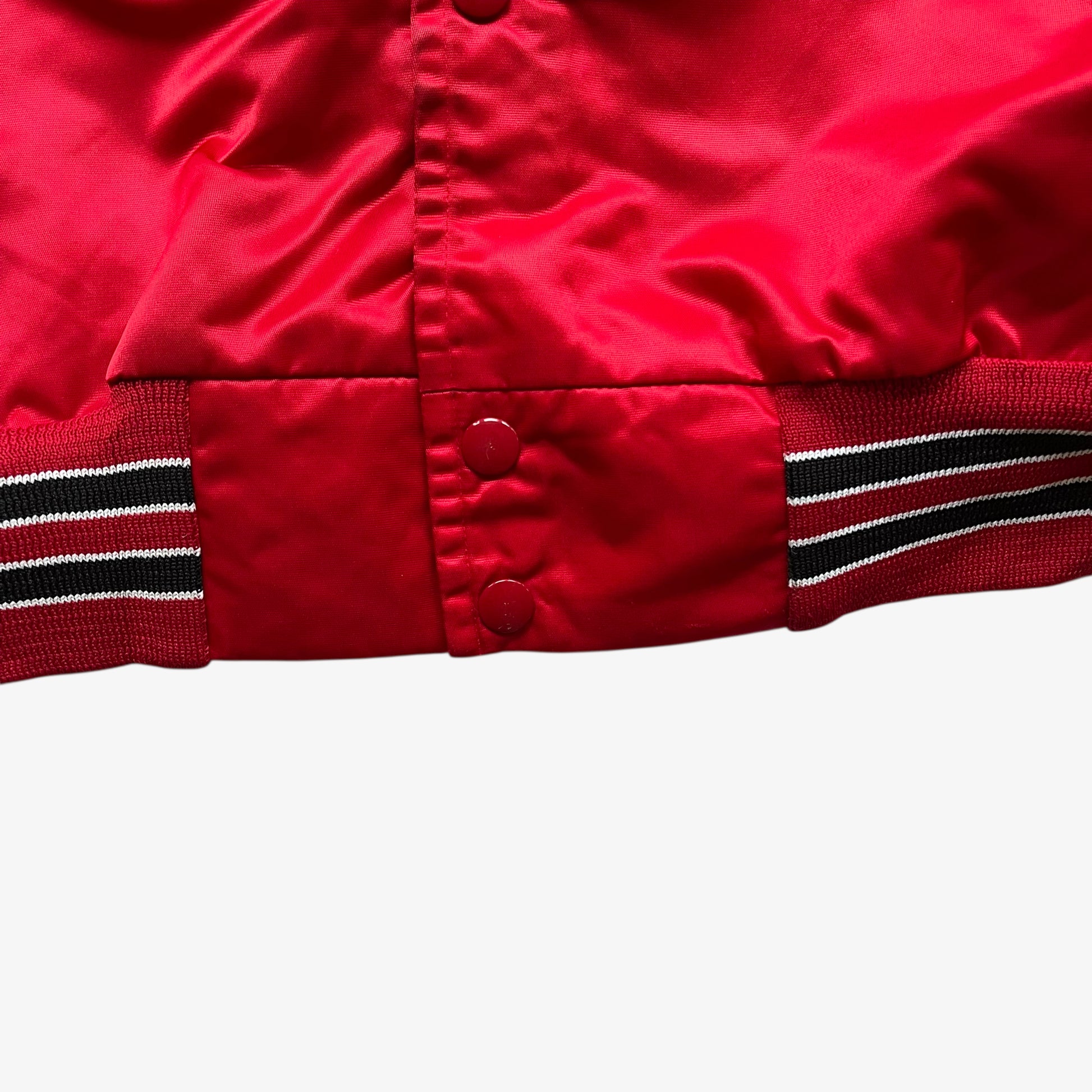 Hem of men's vintage 90s Chalk Line NBA Chicago Bulls red varsity jacket with back embroidered spell out.