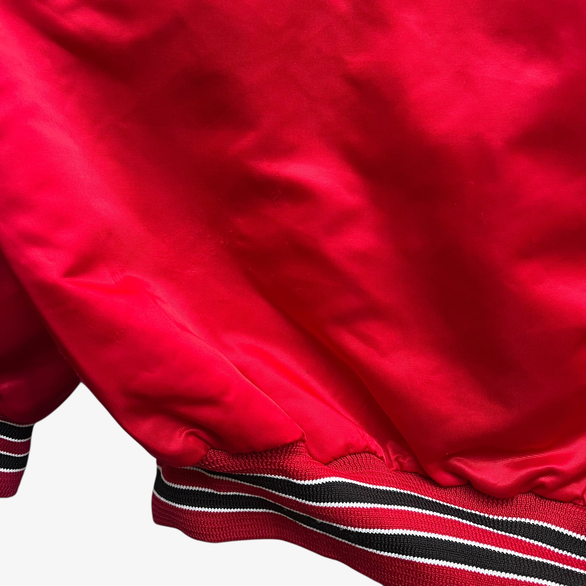 Patina on hem of men's vintage 90s Chalk Line NBA Chicago Bulls red varsity jacket with back embroidered spell out.