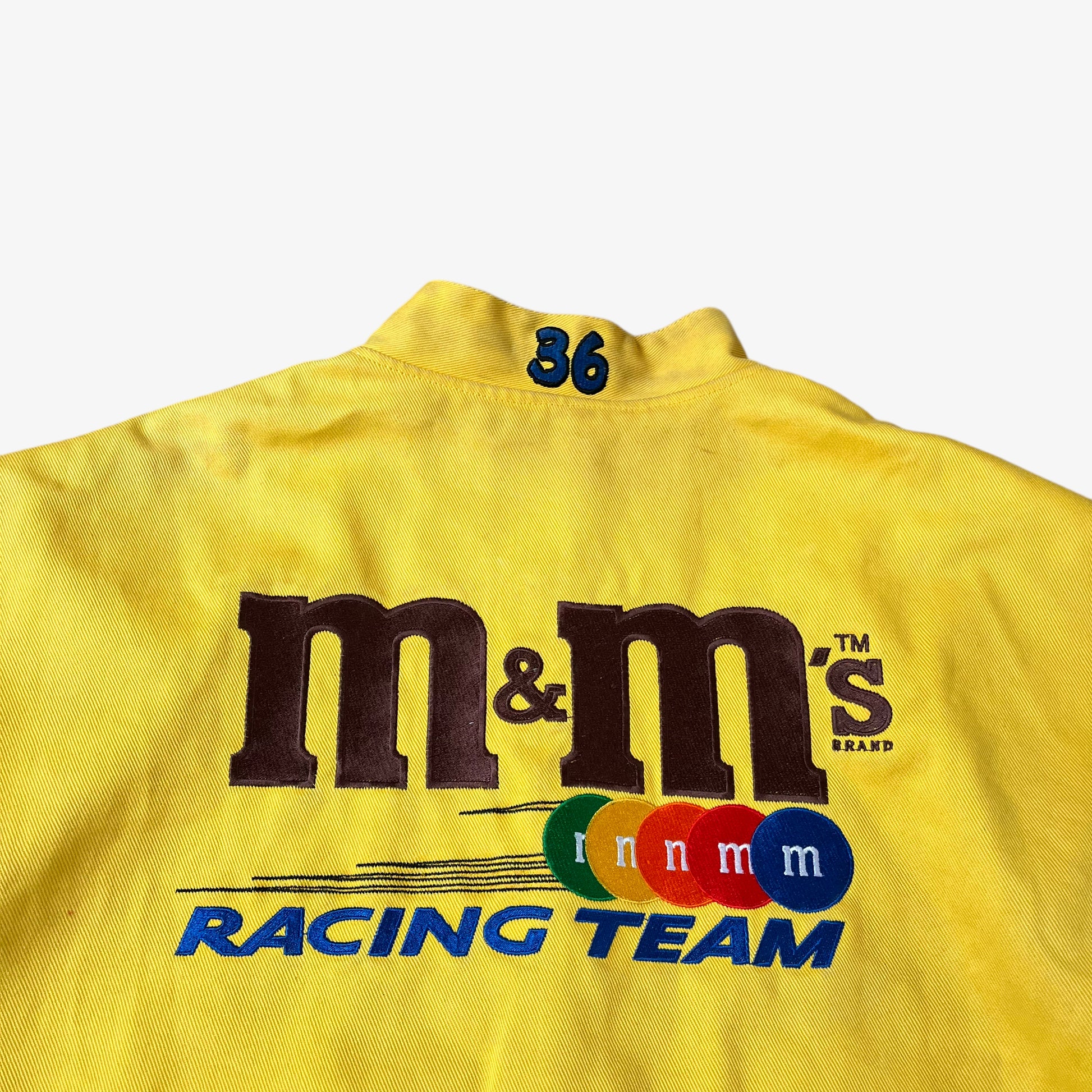 Close up of racing team embroidery of vintage 90s Jeff Hamilton JH Design Ernie Irvan 36 M&M yellow NASCAR jacket.