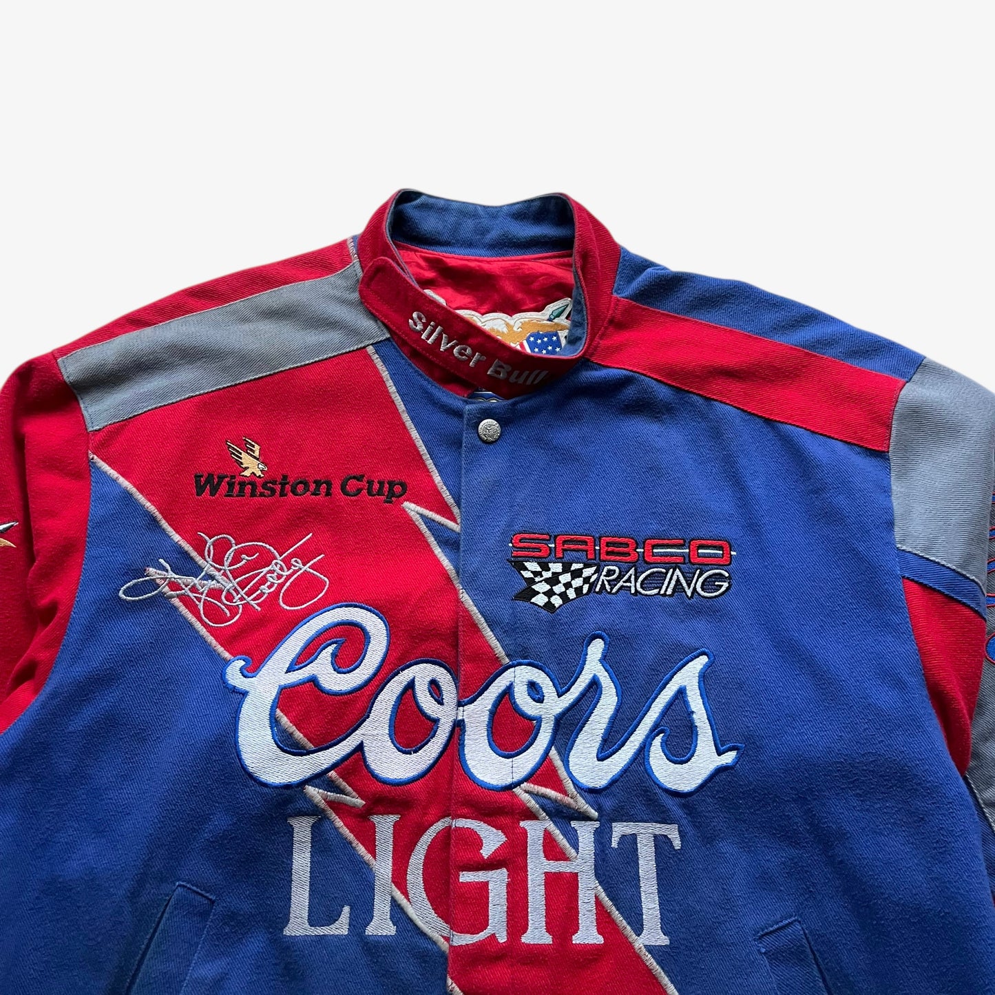 Close up of the embroidery on a vintage 90s men's Jeff Hamilton Coors Light silver bullet nascar jacket.