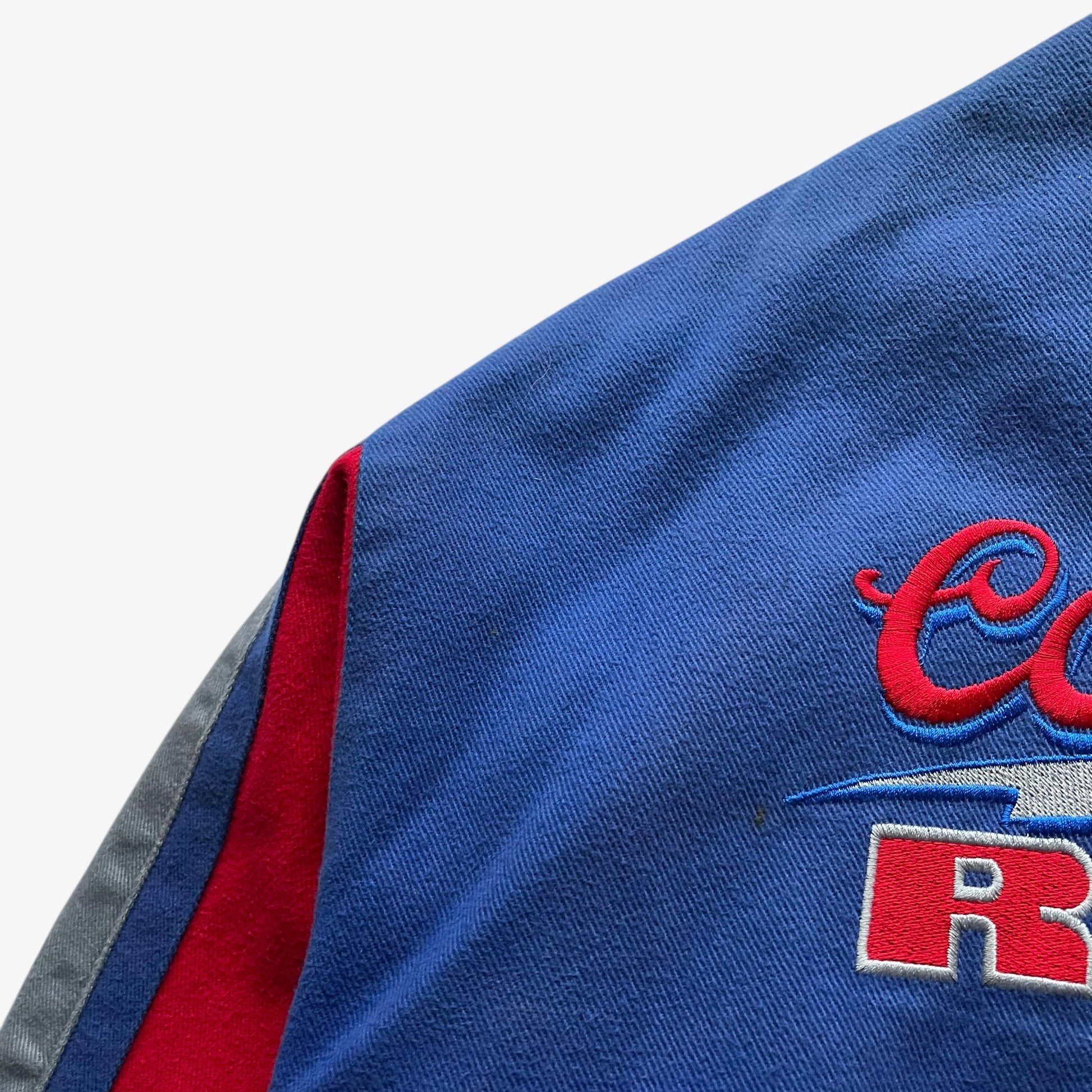 Wear on the back of a vintage 90s men's Jeff Hamilton Coors Light silver bullet nascar jacket.
