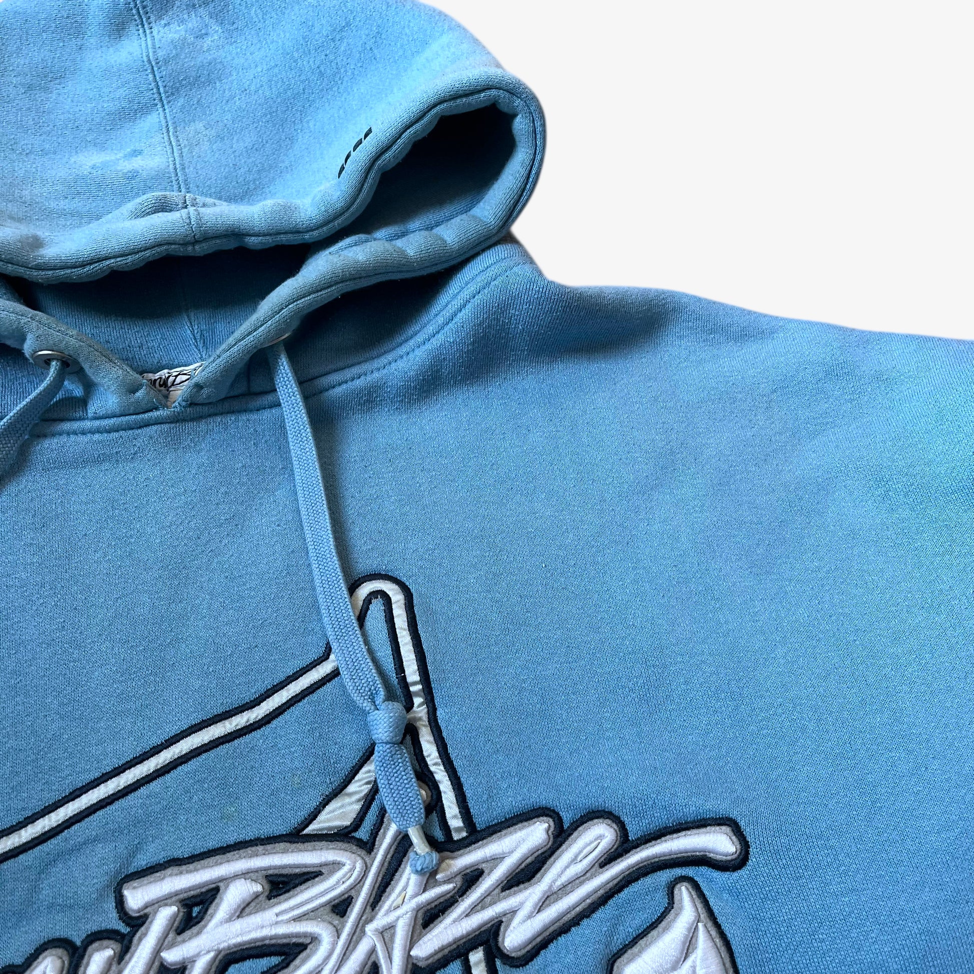 Drawstring pull cord on a vintage 90s men's Johnny Blaze blue hoodie.