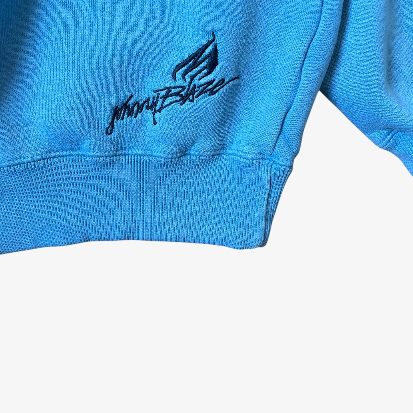 Embroidered Johnny Blaze logo on the hem of a vintage men's blue hoodie.