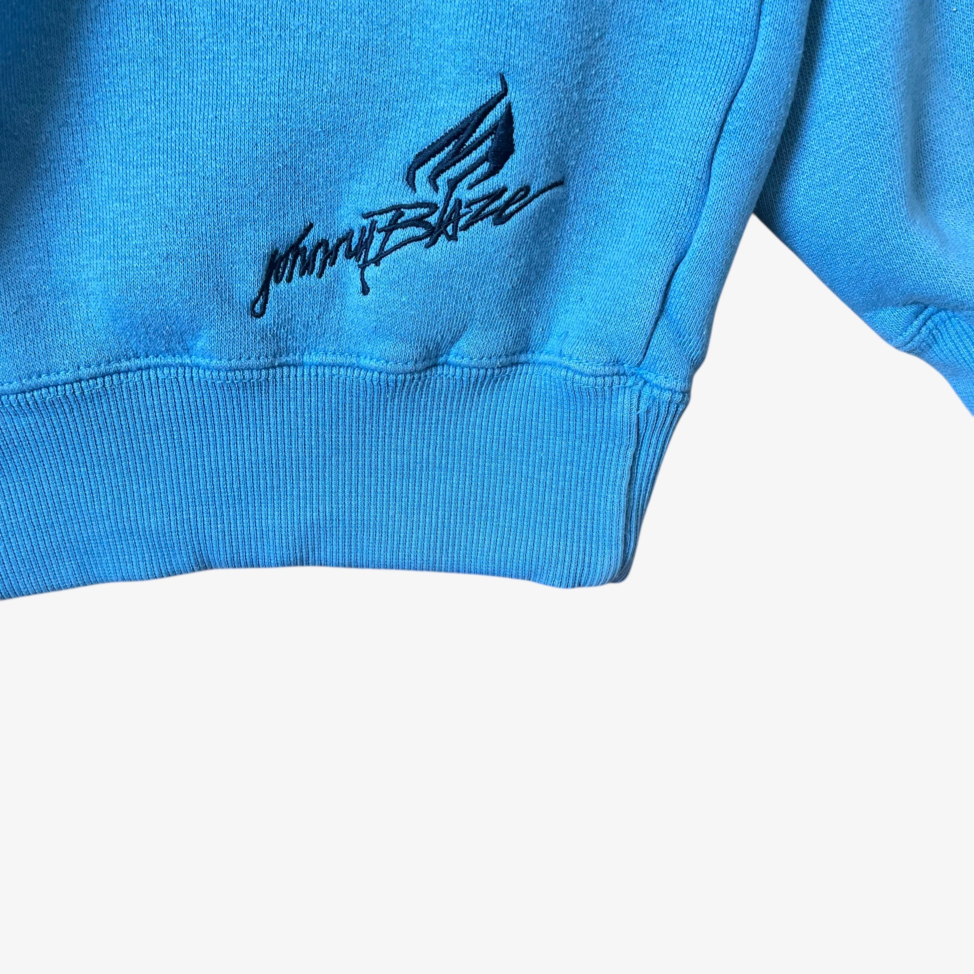 Embroidered Johnny Blaze logo on the hem of a vintage men's blue hoodie.