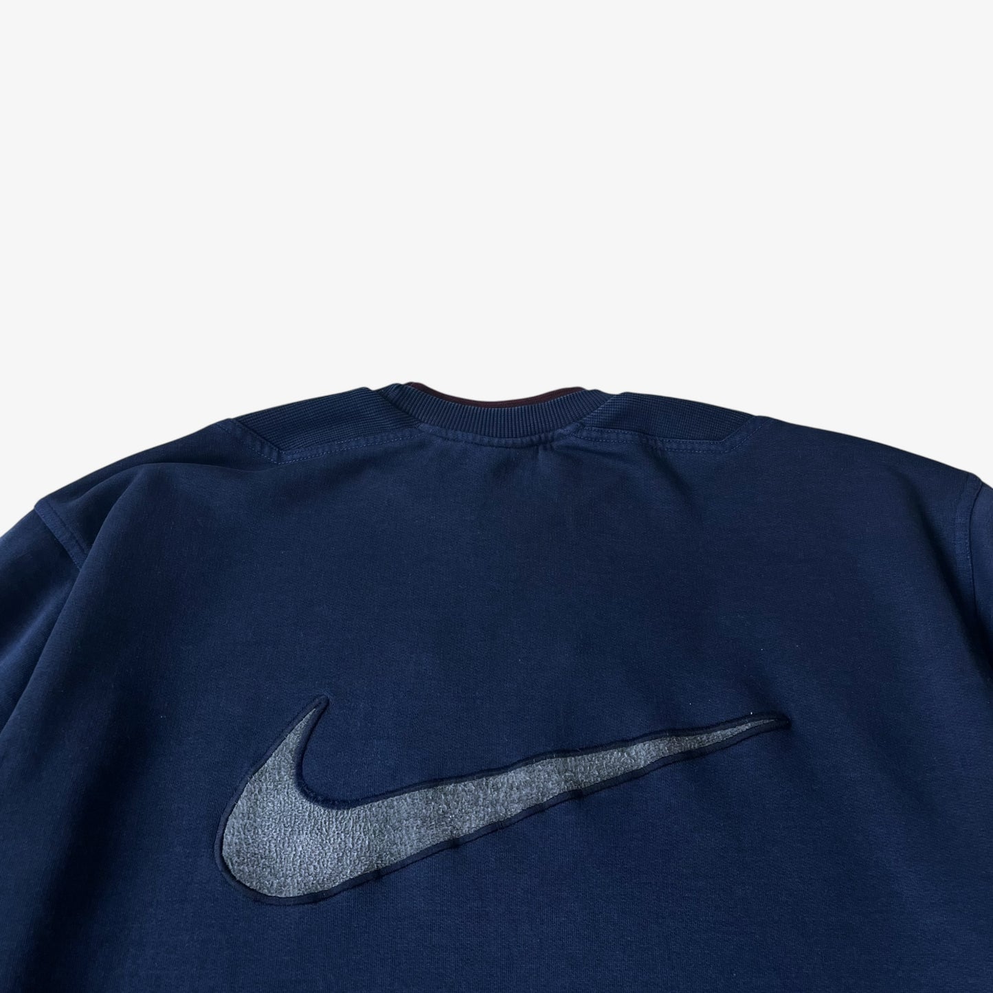 Close up of the back embroidered Nike tick on a vintage PSG sweatshirt.