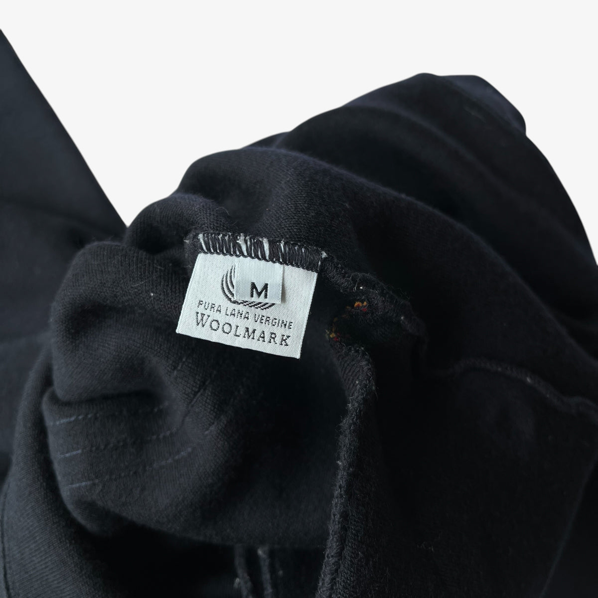 Close-up of a navy wool quarter zip fleece showing the inner pure new wool label.
