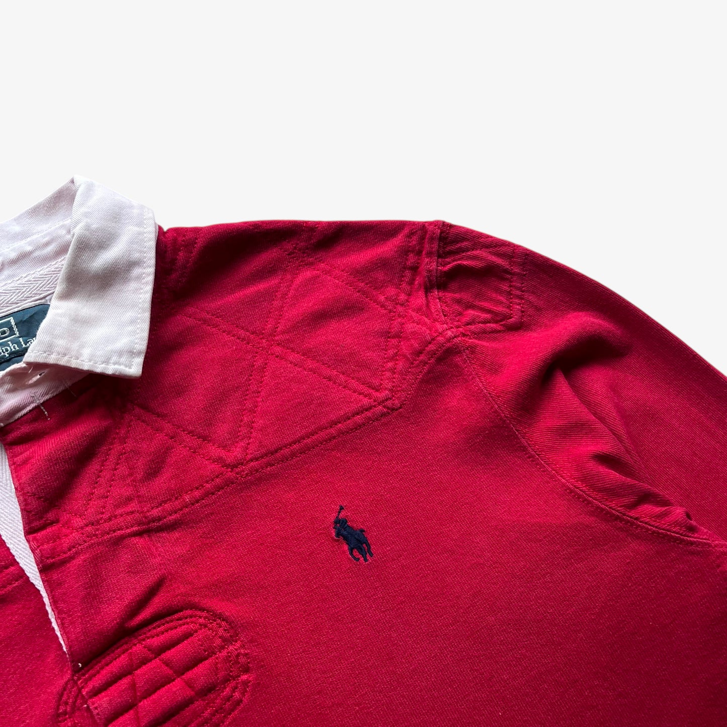 Embroidered polo player logo on vintage 90s men's Ralph Lauren red rugby shirt with contrasting collar.