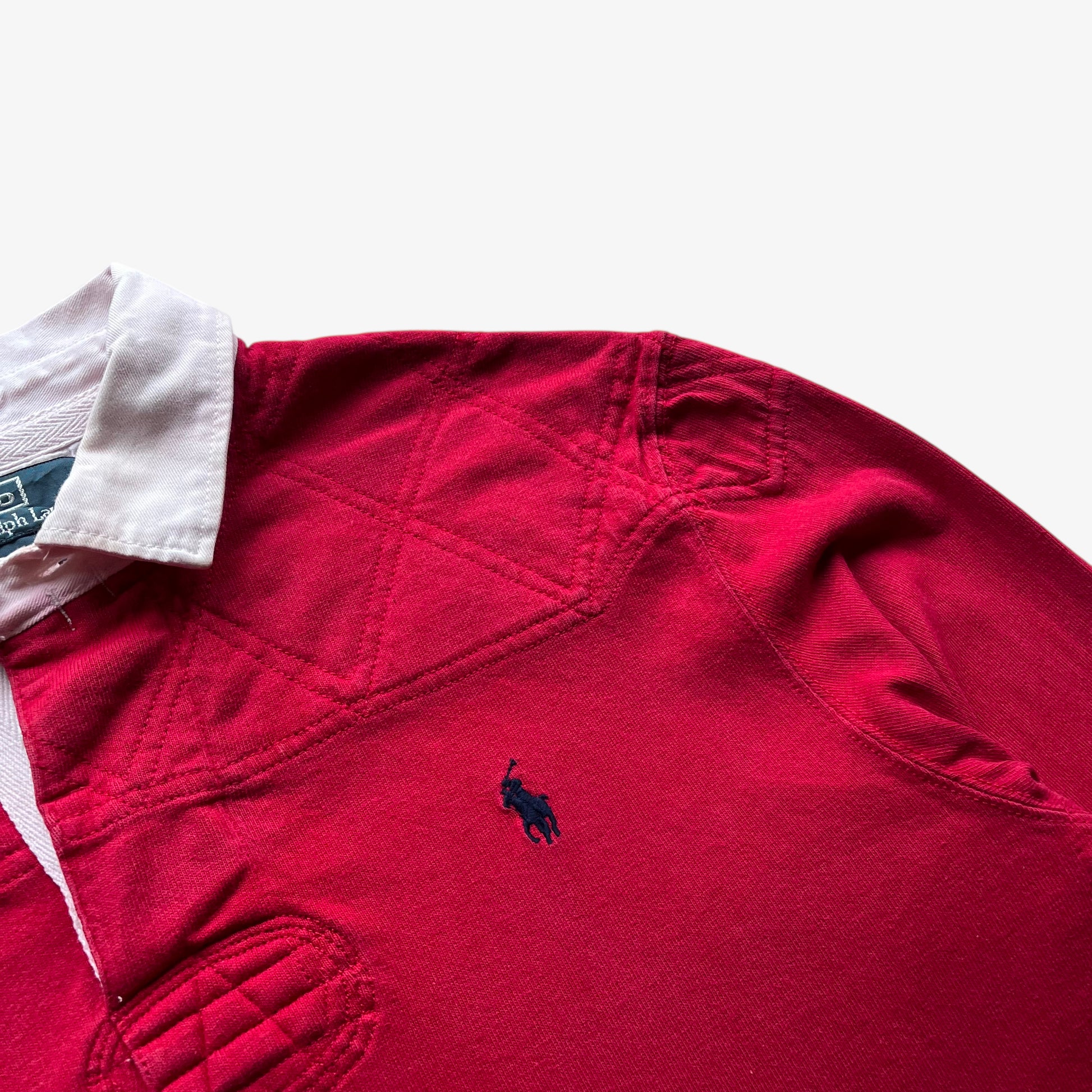 Embroidered polo player logo on vintage 90s men's Ralph Lauren red rugby shirt with contrasting collar.