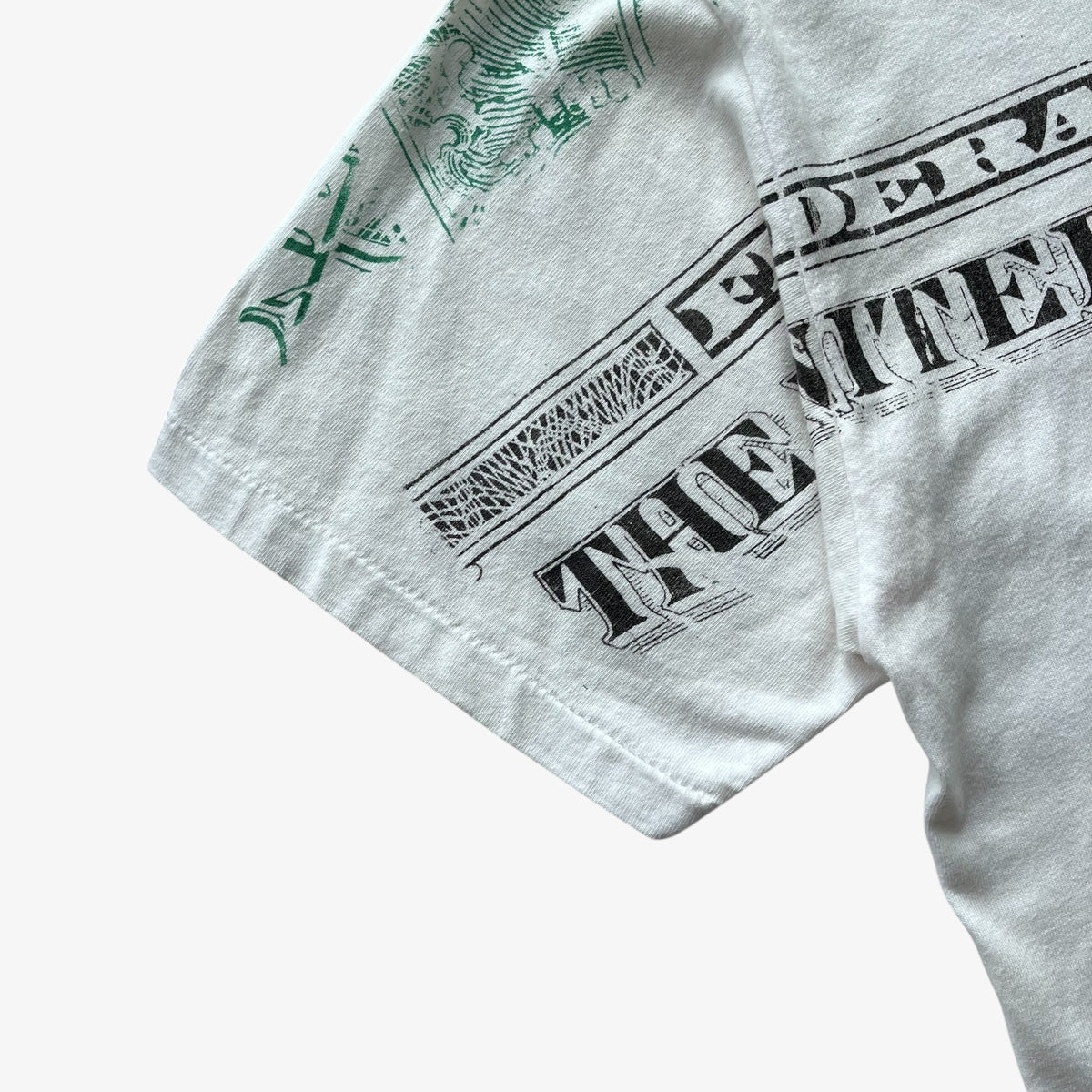 Close-up of a vintage 90s white t-shirt sleeve featuring a black distressed graphic of a U.S.