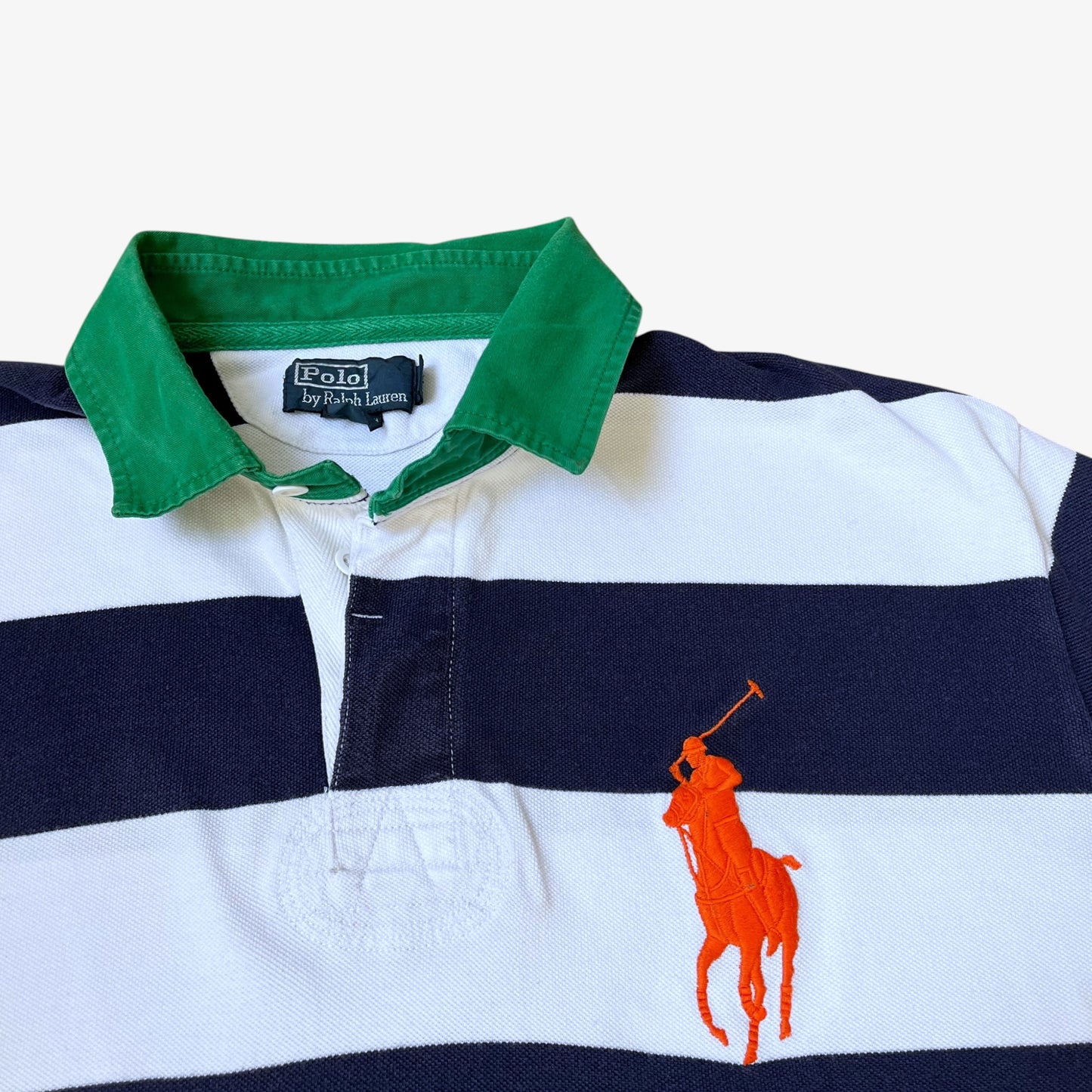 Close up of large embroidered polo player logo on a vintage 90s men's Ralph Lauren navy and white striped shirt.