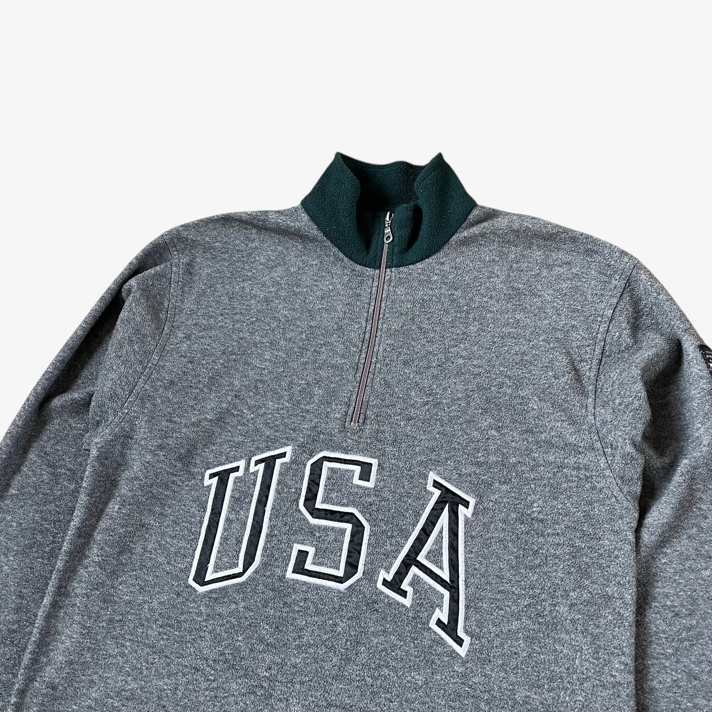 Close up to a Ralph Lauren grey pullover with 'USA' text on a light grey background