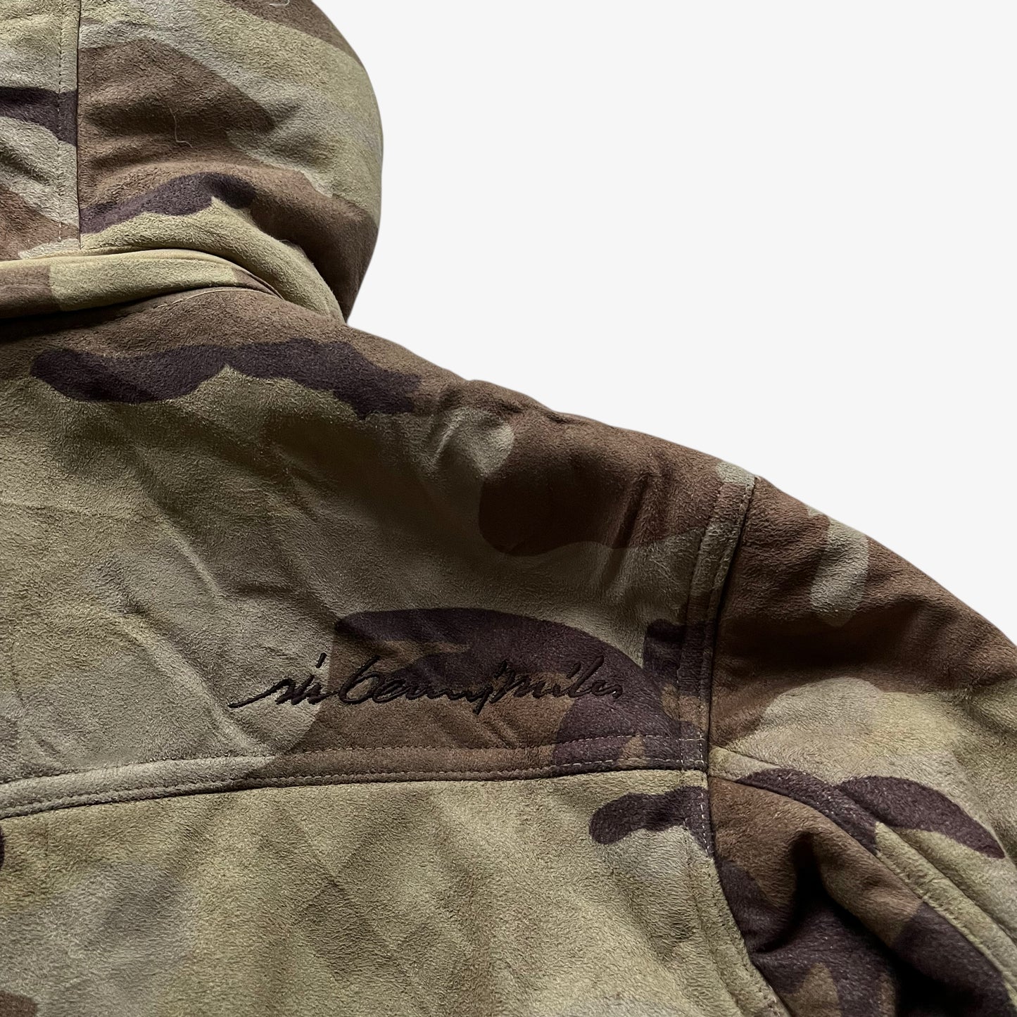 Back spell out logo on vintage 90s men's Sir Benni Miles green camouflage jacket featuring a faux fur hood.