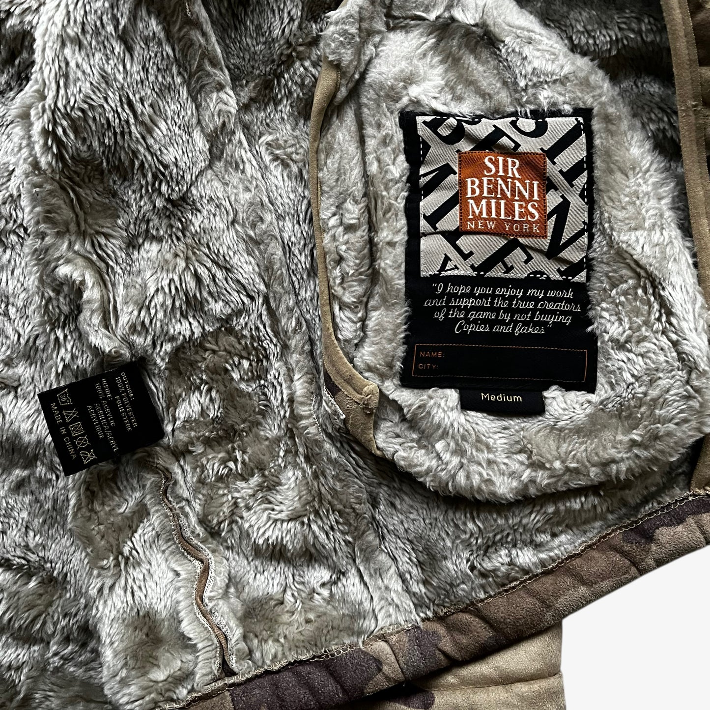Sir Benni Miles label stitched inside the sherpa lining of a vintage 90s men's green camouflage jacket featuring a faux fur hood.