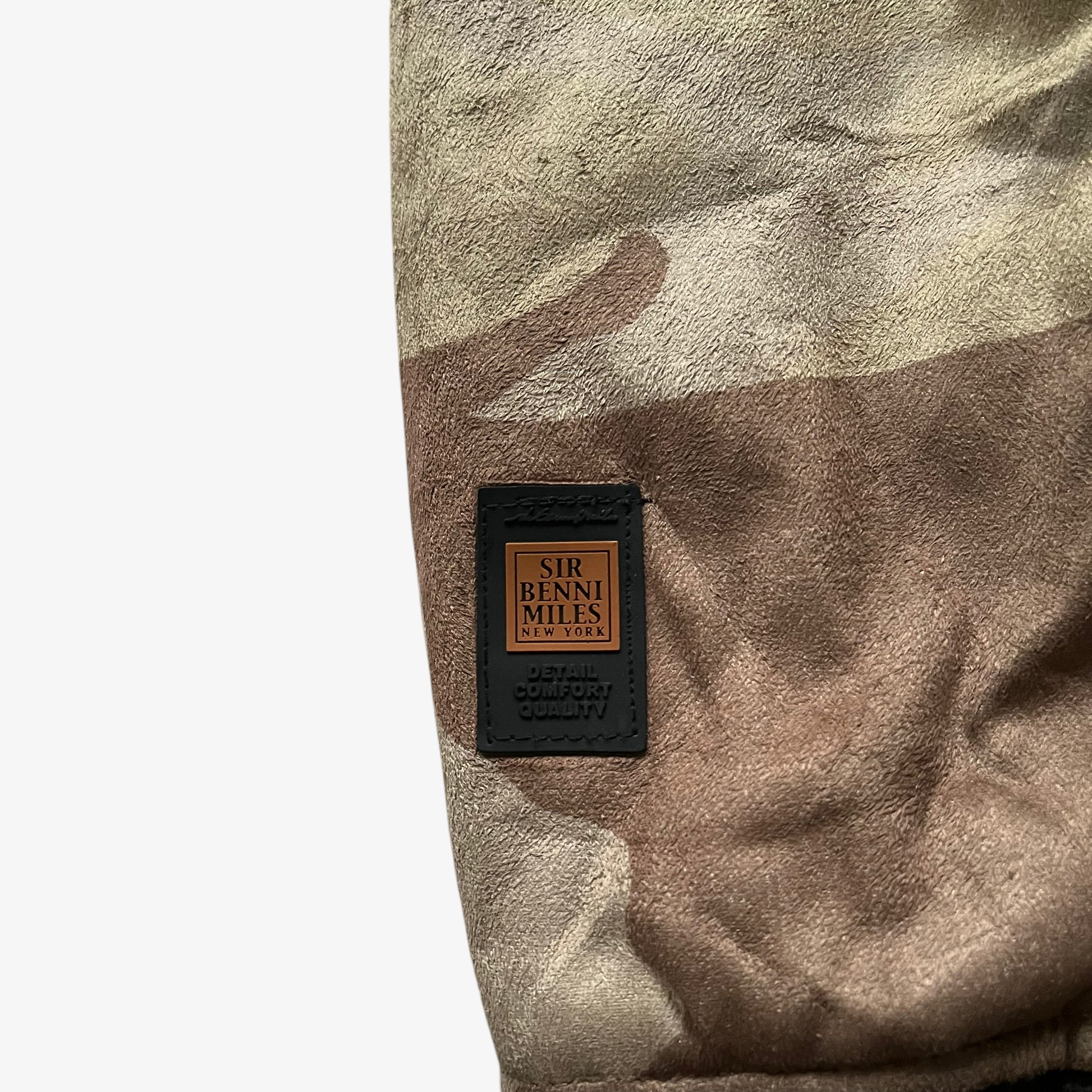 Embroidered logo of vintage 90s men's Sir Benni Miles green camouflage jacket featuring a faux fur hood.