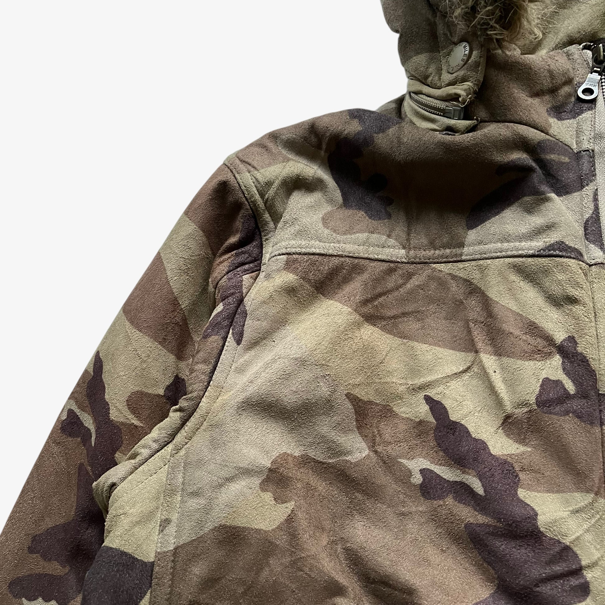 Patina of vintage 90s men's Sir Benni Miles green camouflage jacket featuring a faux fur hood.