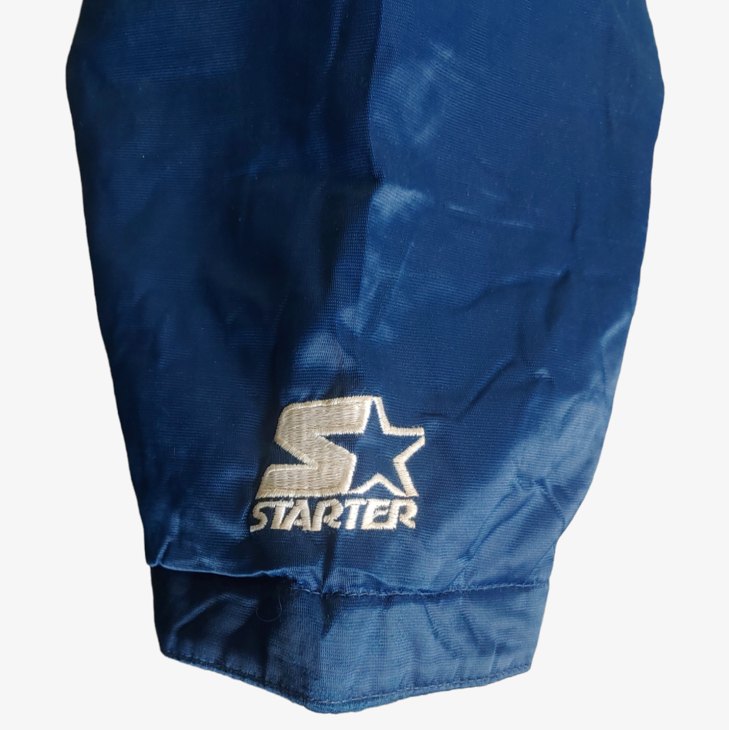 Embroidered cuff on vintage Starter MLB Cleveland Indians jacket in blue with red and white accents.