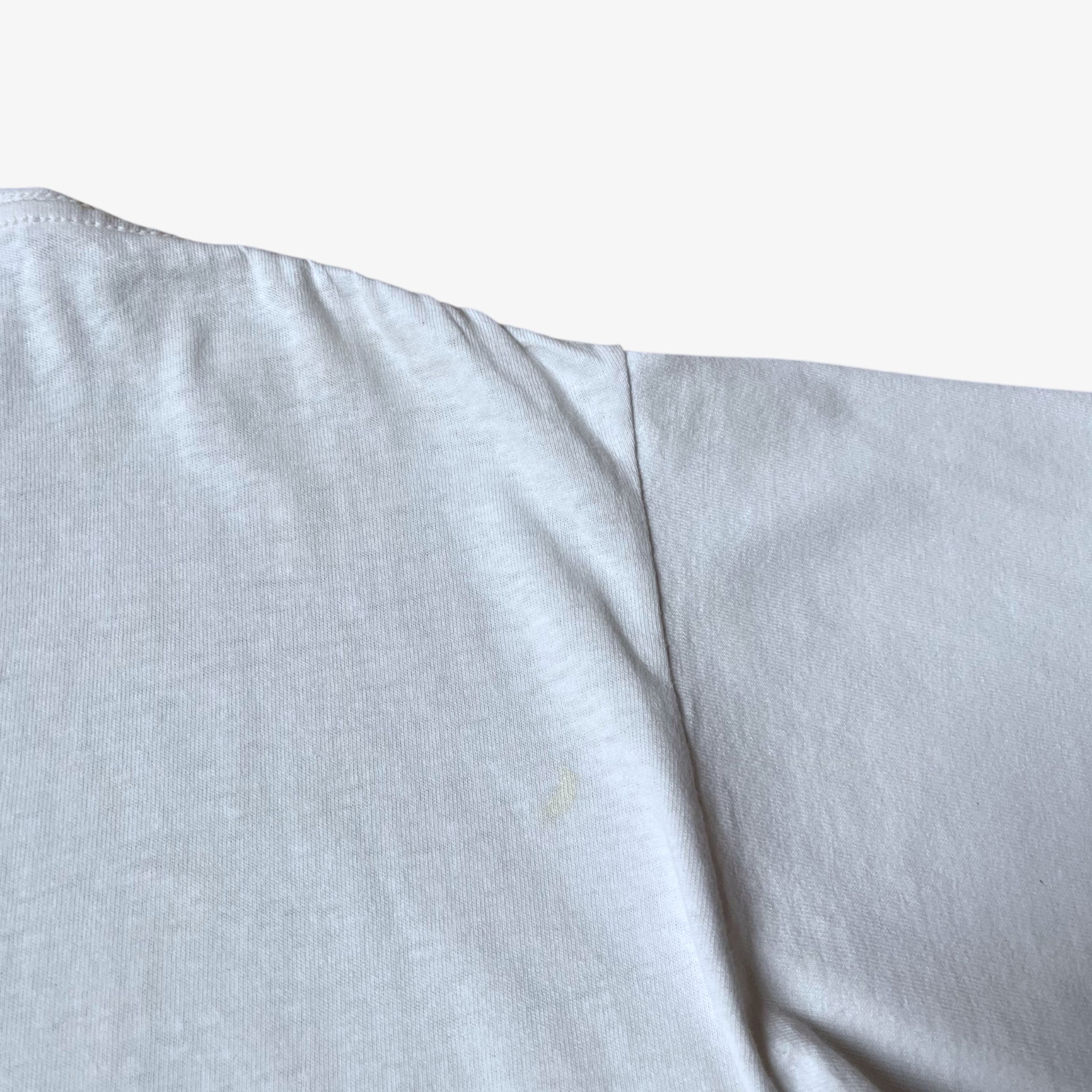 Back wear on vintage 90s men's Stussy studio Jamaica reggae dance hall print white single stitch thrashed t-shirt.