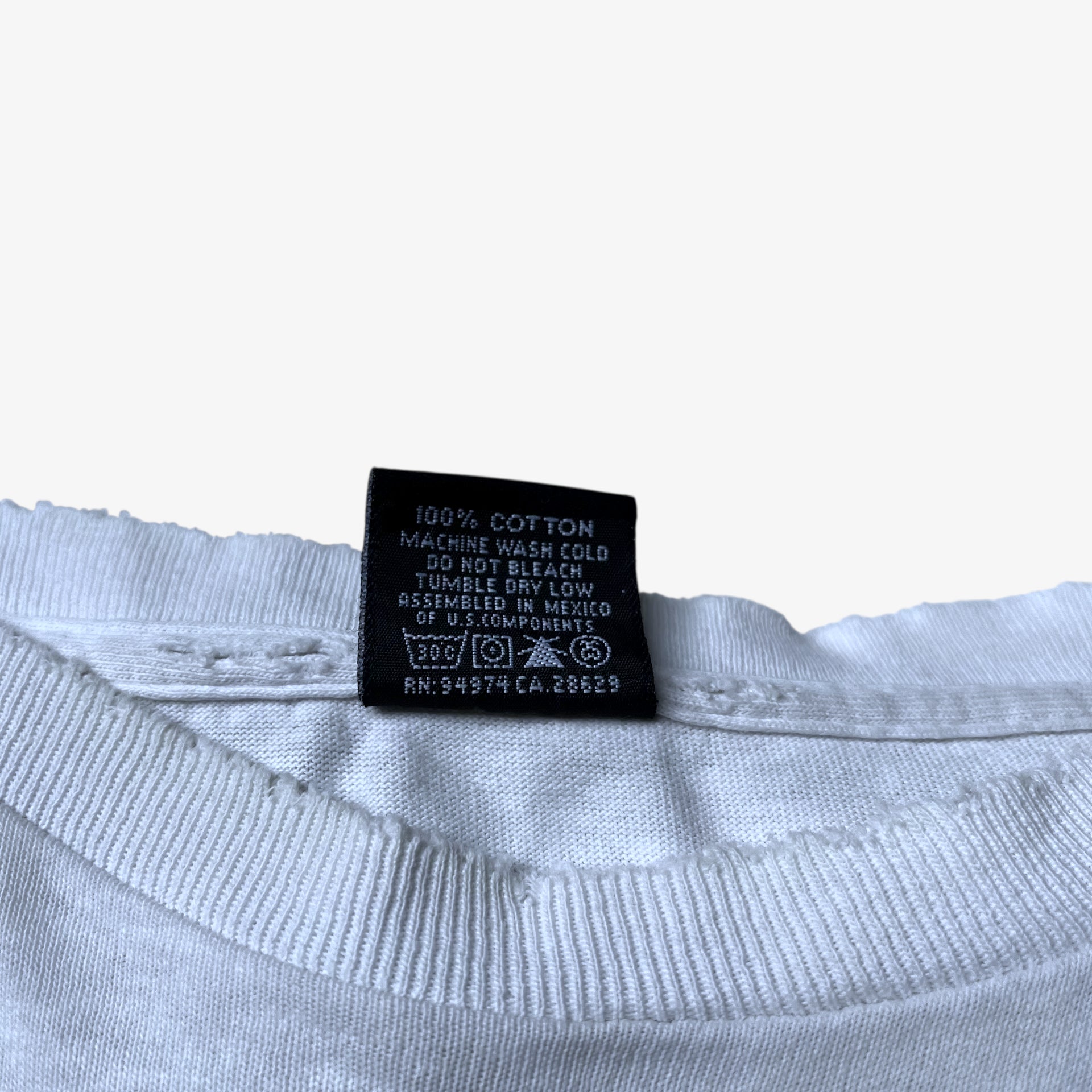 Back of label inside of vintage 90s men's Stussy studio Jamaica reggae dance hall print white single stitch thrashed t-shirt.