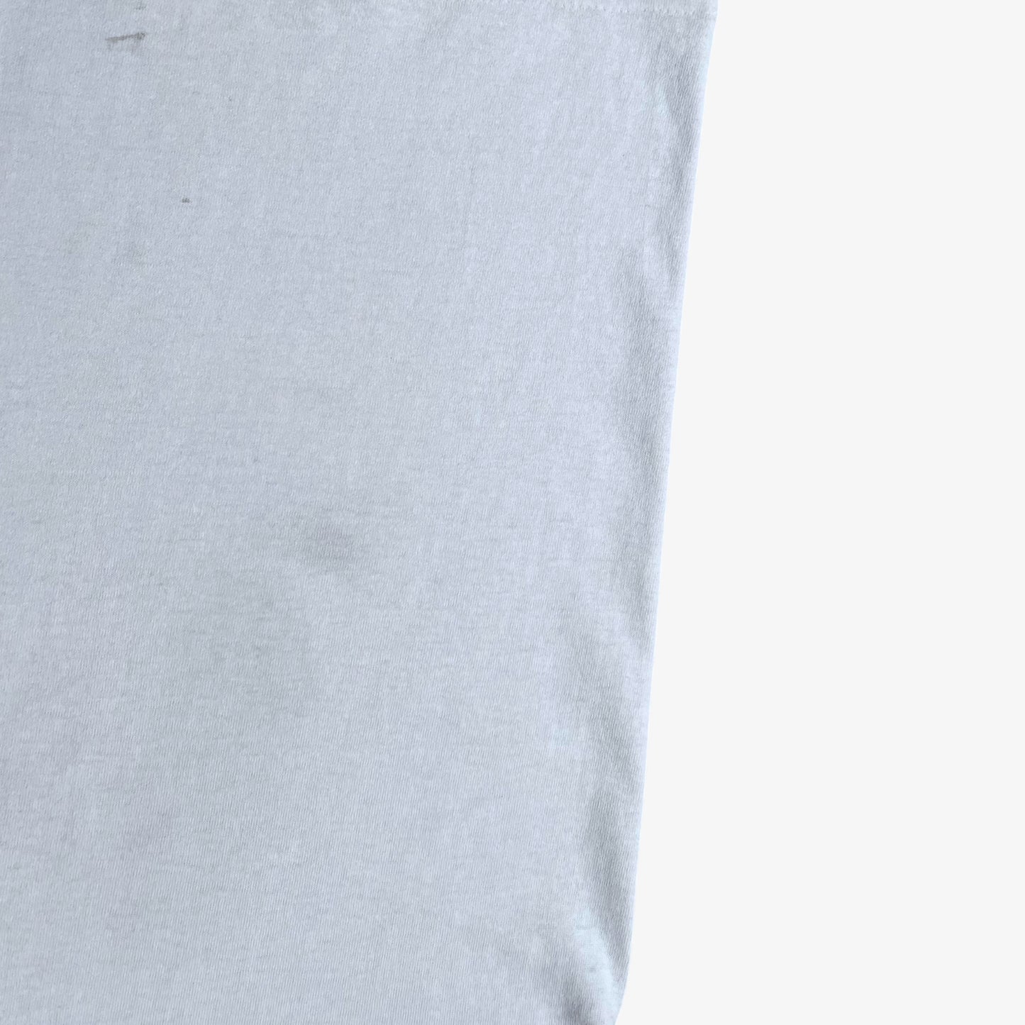 Close up of wear on vintage 90s men's Stussy studio Jamaica reggae dance hall print white single stitch thrashed t-shirt.