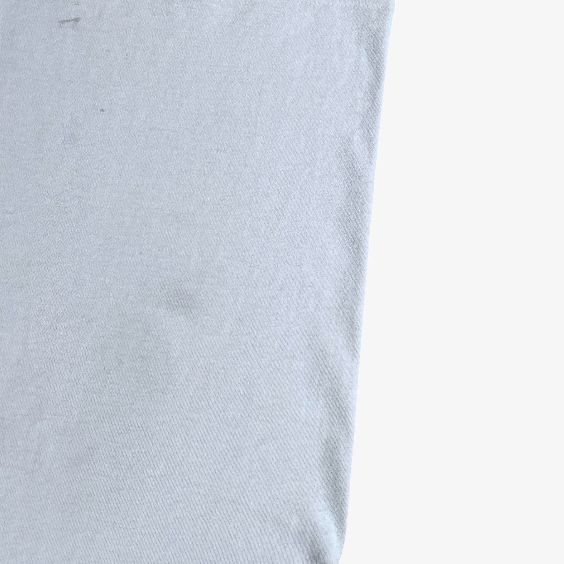 Close up of wear on vintage 90s men's Stussy studio Jamaica reggae dance hall print white single stitch thrashed t-shirt.