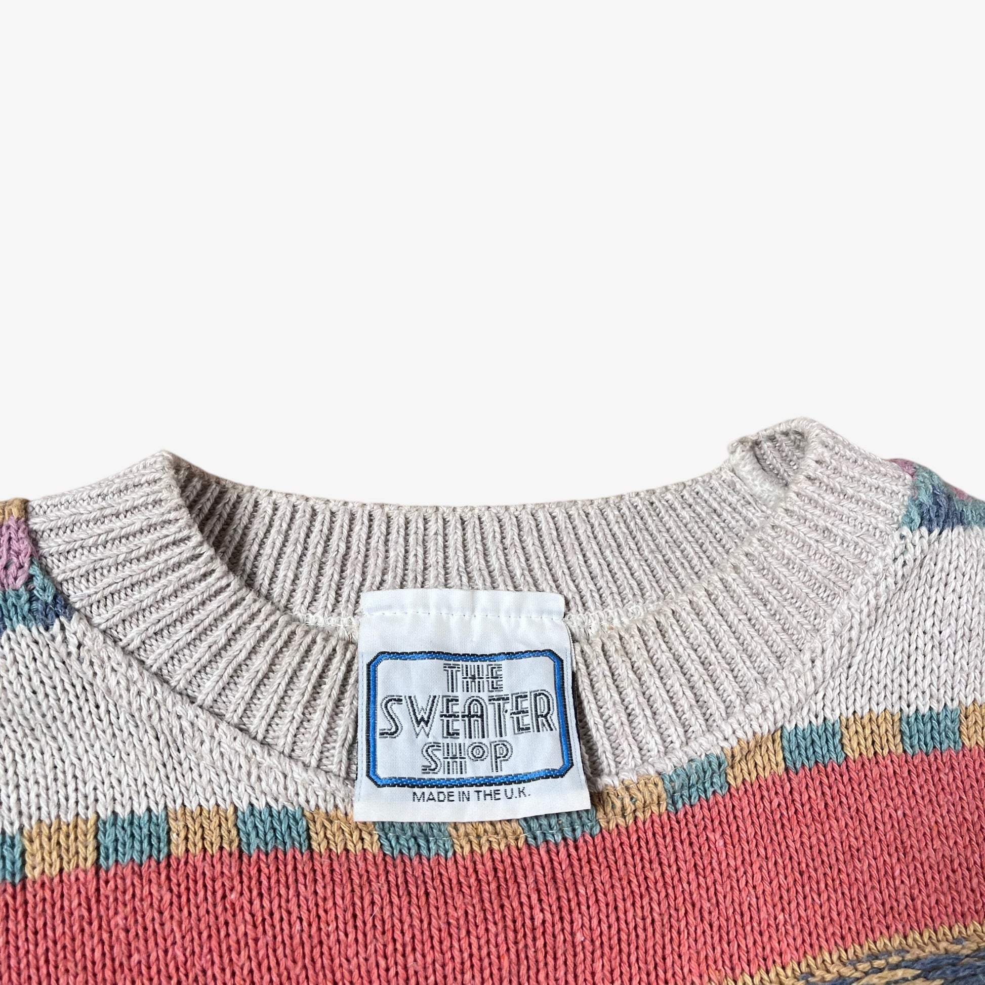 Close-up of a sweater with a label from 'The Sweater Shop' on a white background