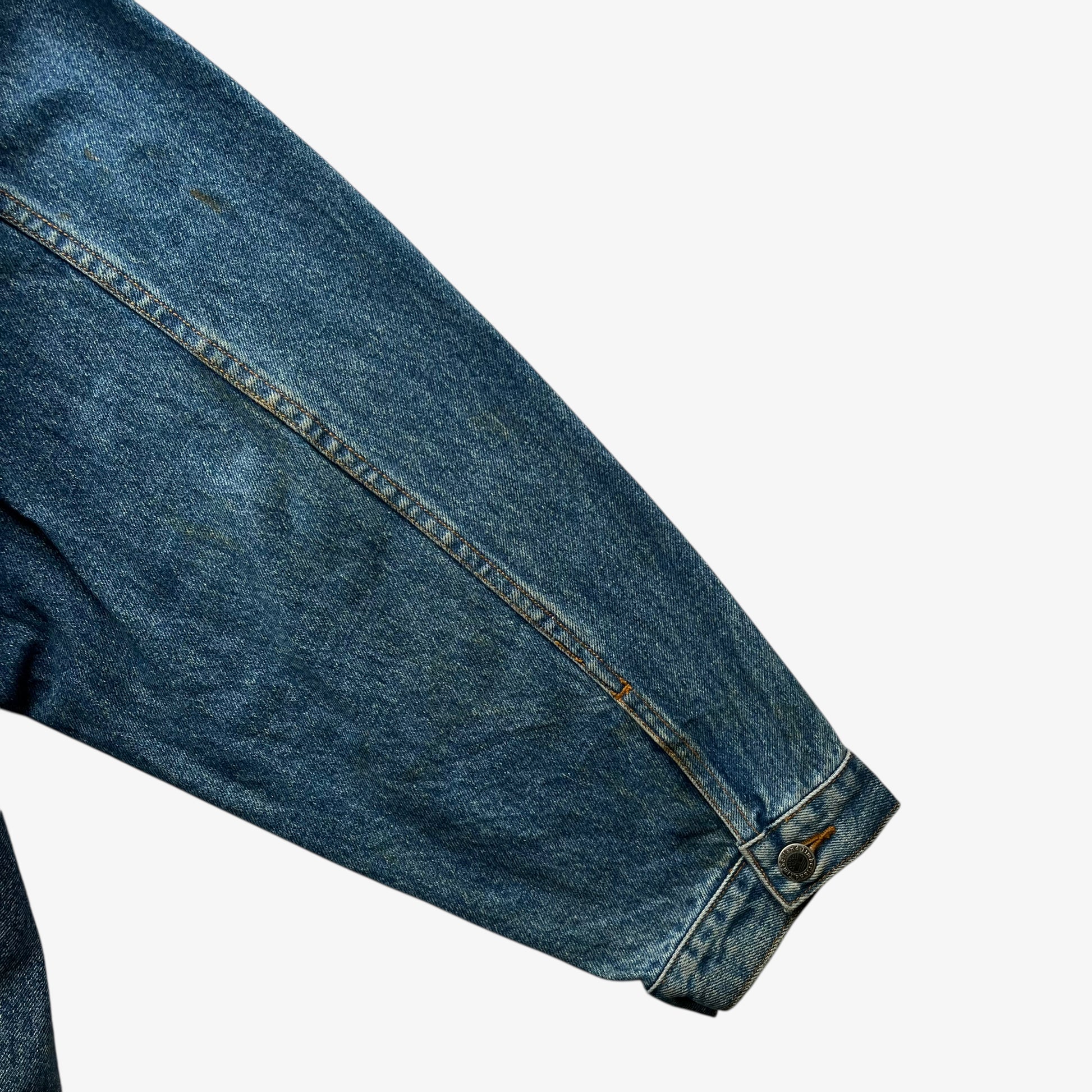 Patina on sleeve of men's vintage 90s Timberland blue denim jacket with leather collar and Looney Tunes Marvin Martian print.