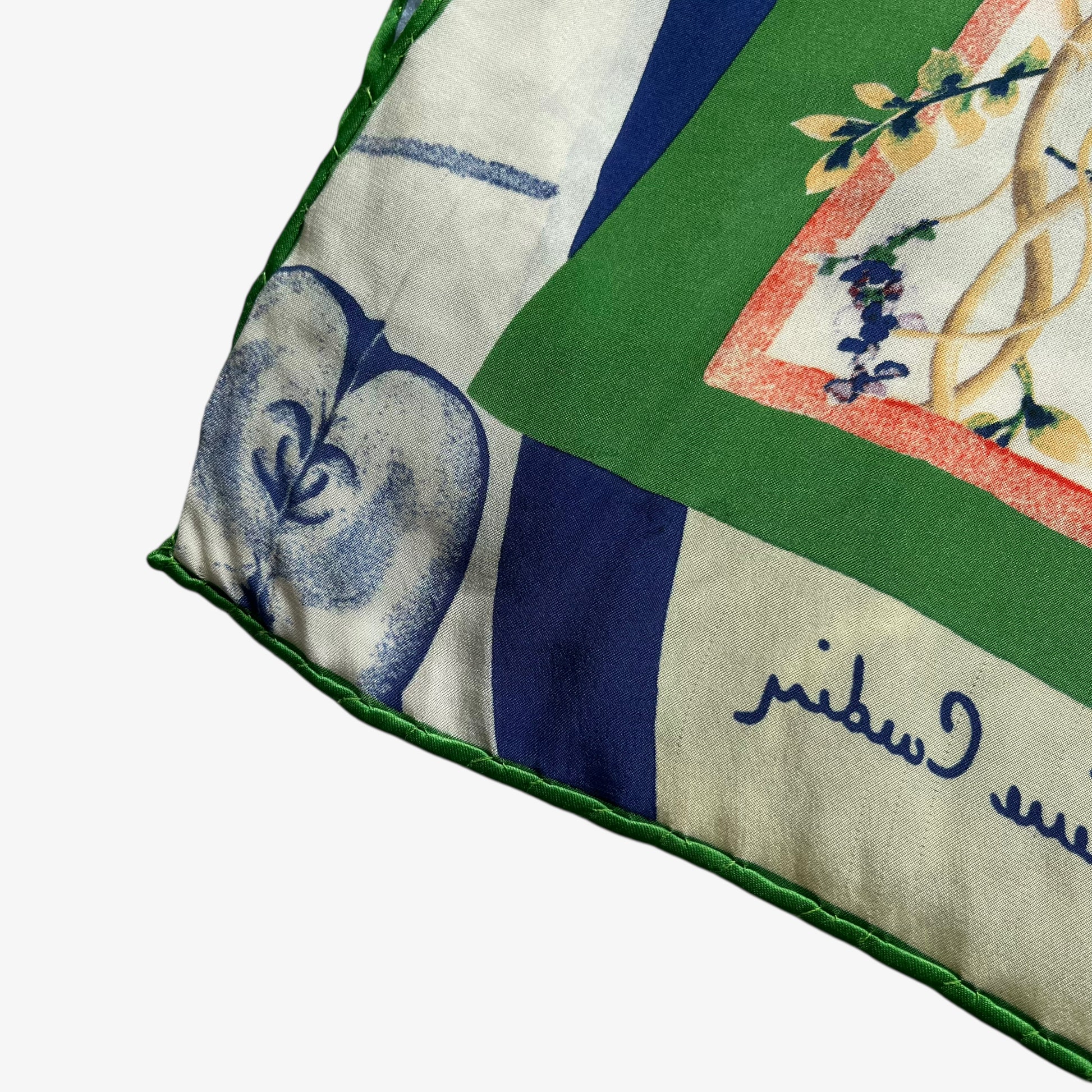 Hand rolled edges of women's vintage 90s Pierre Cardin colourful floral and fruit print silk scarf.