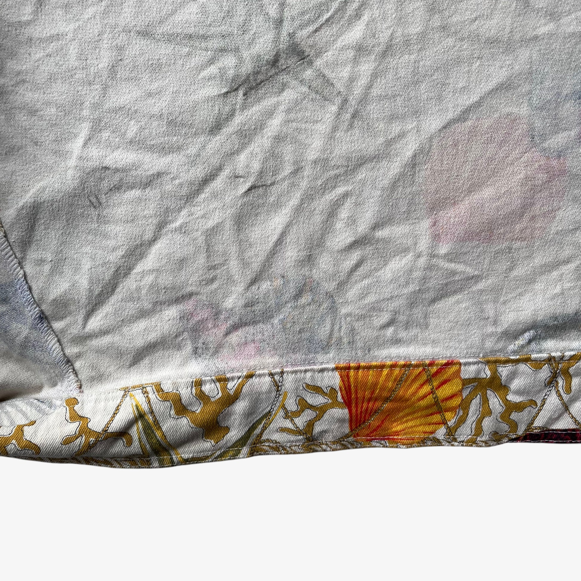 Hem of vintage 90s women's Christian Llinares CL2 nautical seashell print gold trucker jacket.