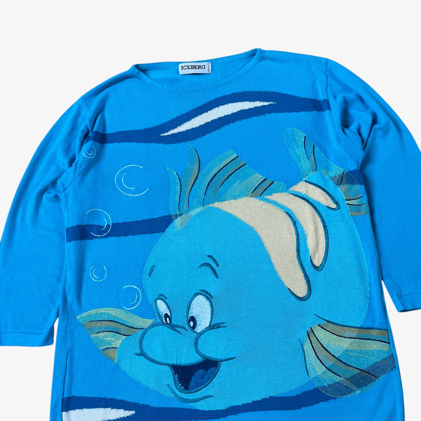 Close up of vintage 90s ICEBERG women’s blue knitted jumper with 1991 Disney Little Mermaid Flounder embroidered design.