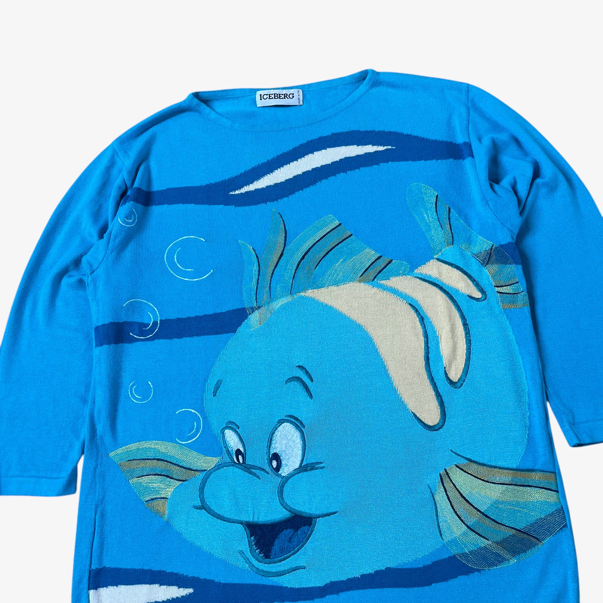 Close up of vintage 90s ICEBERG women’s blue knitted jumper with 1991 Disney Little Mermaid Flounder embroidered design.