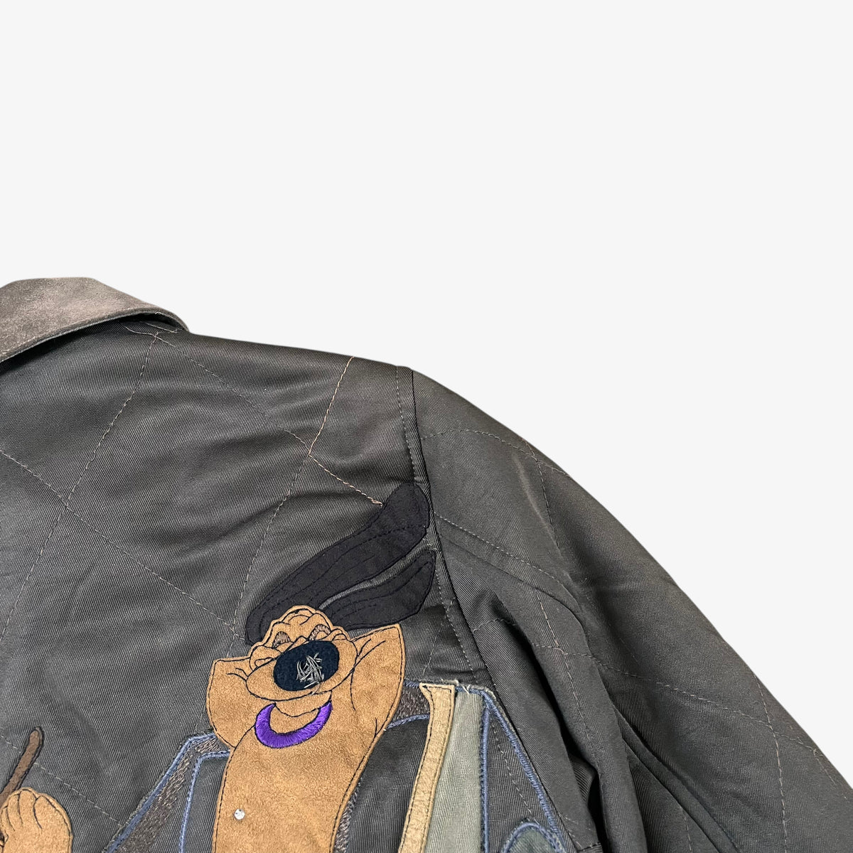 Close up of wear on vintage 90s Iceberg women’s khaki quilted bomber jacket with Disney Aristocats embroidery.