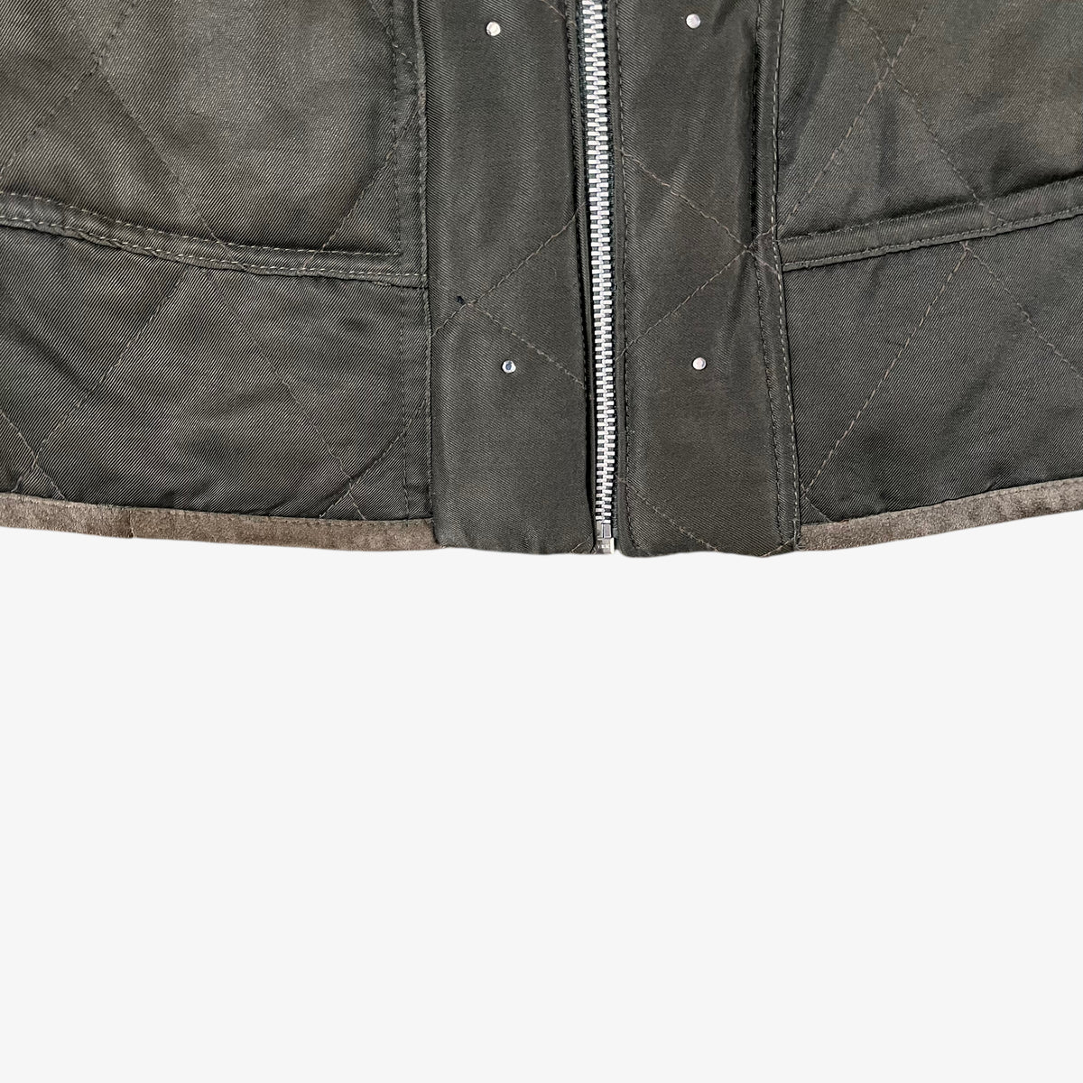 Hem of vintage 90s Iceberg women’s khaki quilted bomber jacket with Disney Aristocats embroidery and brown leather collar.