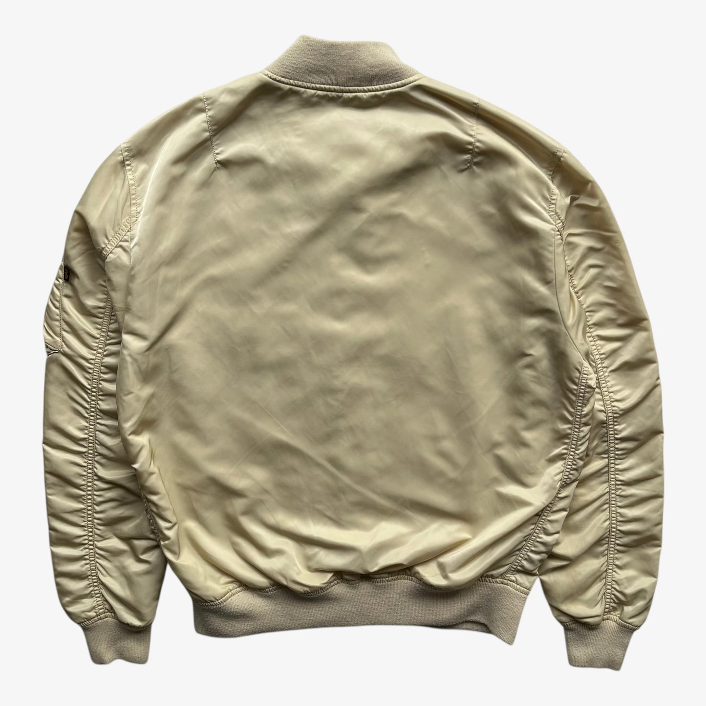 Back of vintage Y2K men's Alpha Industries beige bomber jacket.