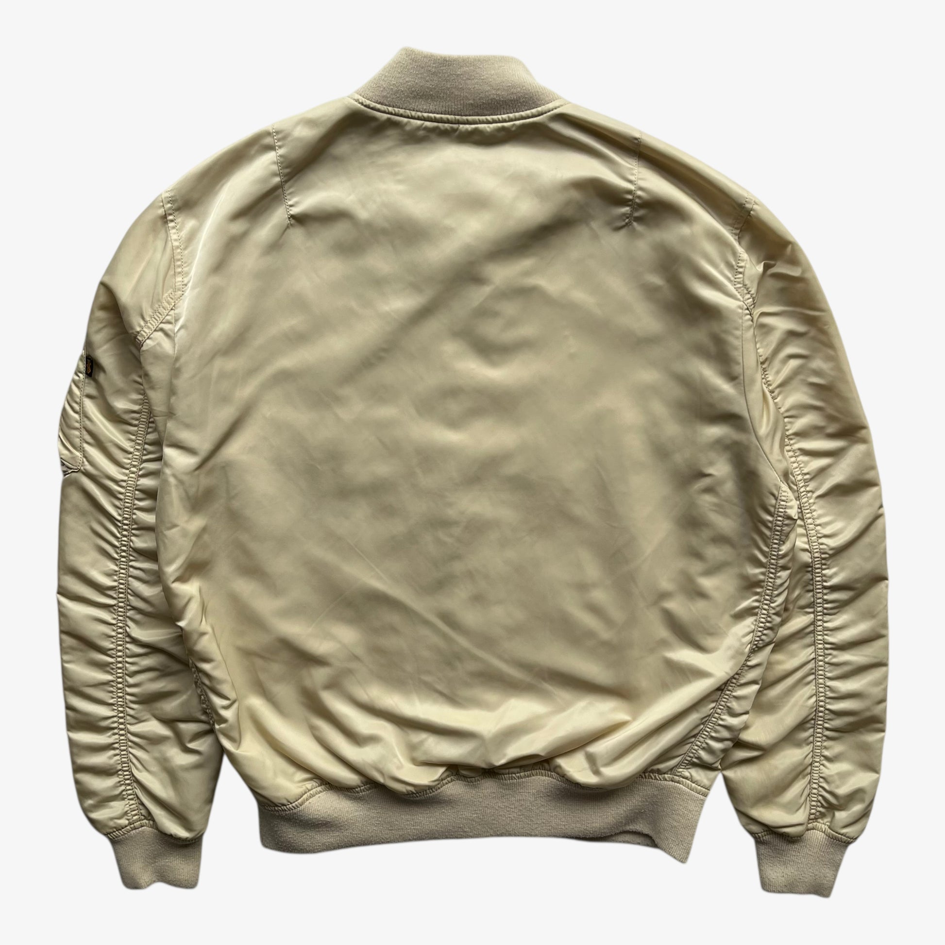 Back of vintage Y2K men's Alpha Industries beige bomber jacket.