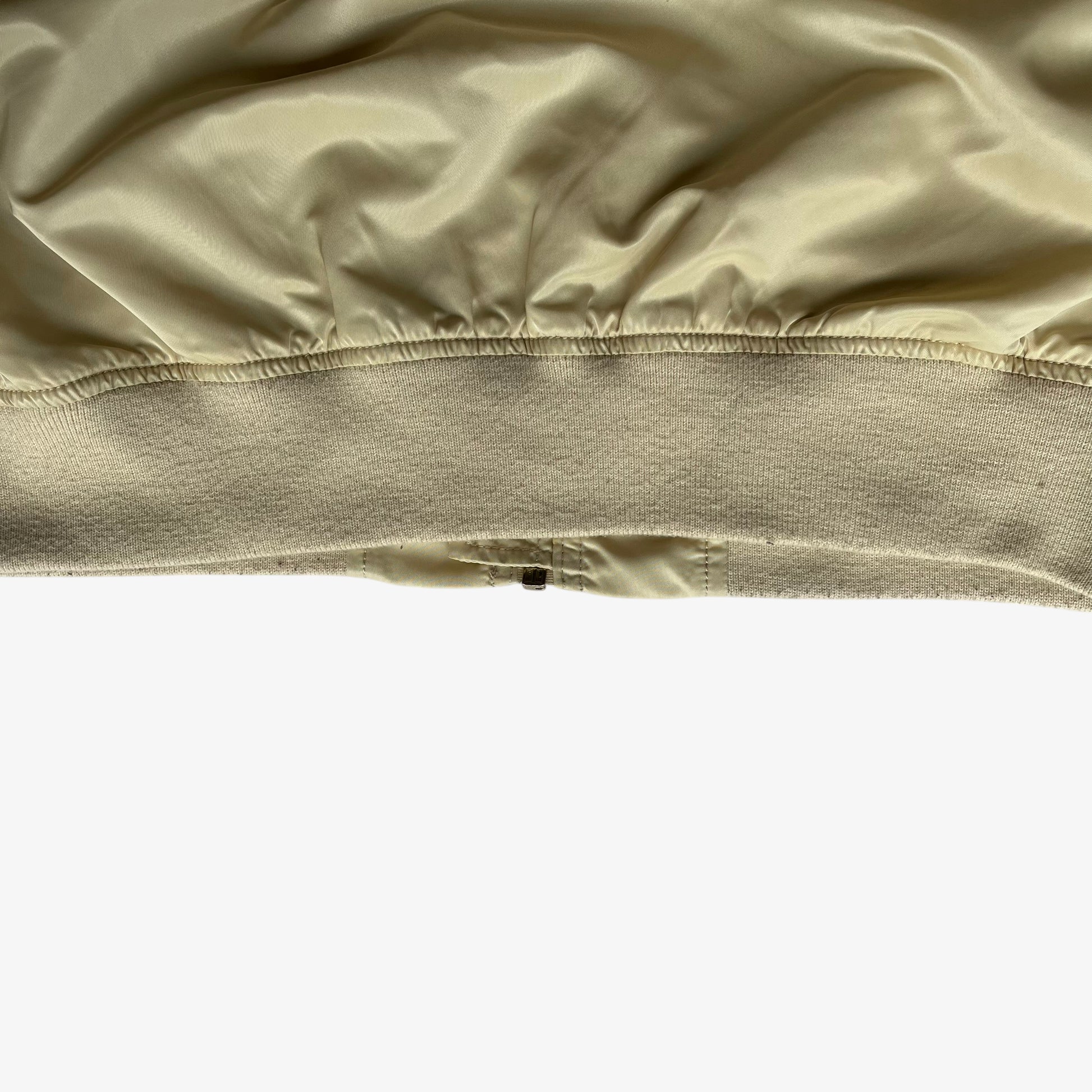 Hem of vintage Y2K men's Alpha Industries beige bomber jacket.