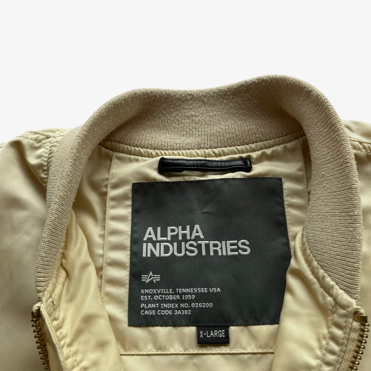 Alpha Industries label stitched inside of vintage Y2K men's beige bomber jacket.
