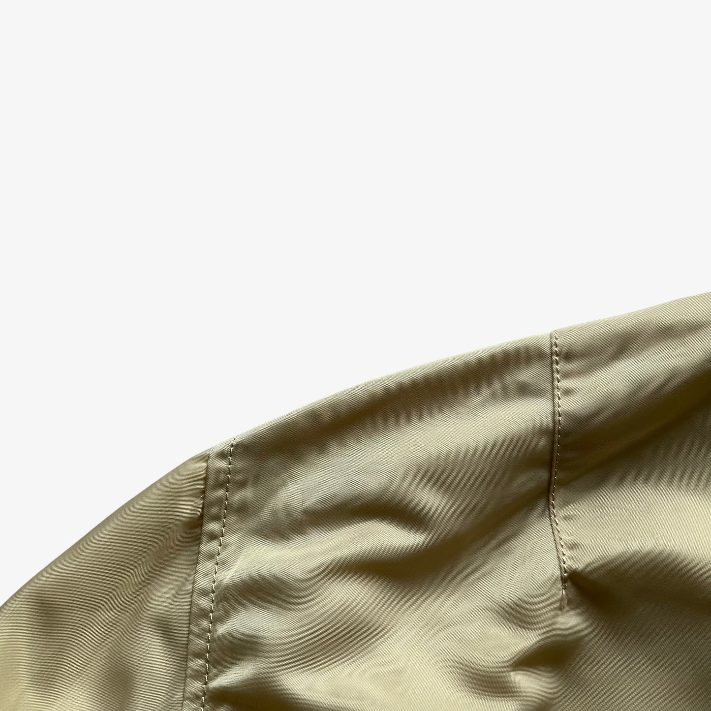 Patina on vintage Y2K men's Alpha Industries beige bomber jacket.