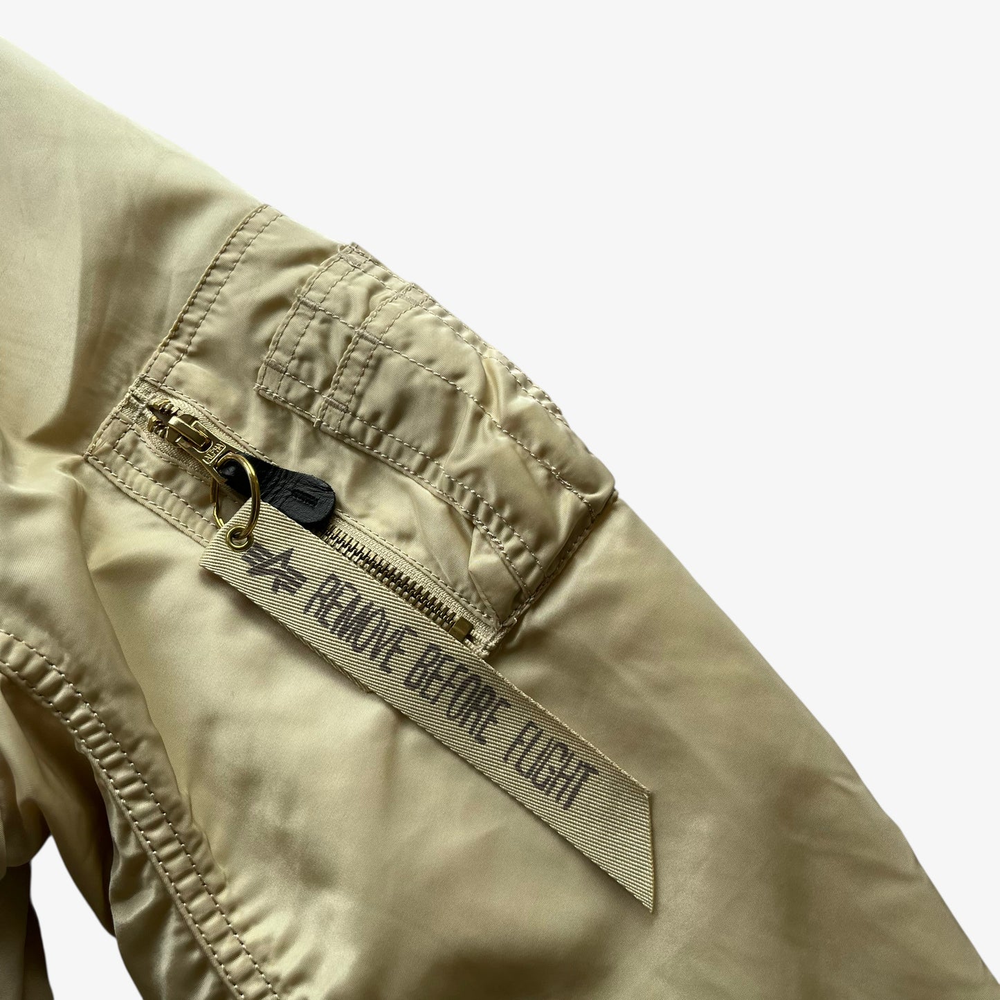 Sleeve pocket on vintage Y2K men's Alpha Industries beige bomber jacket.