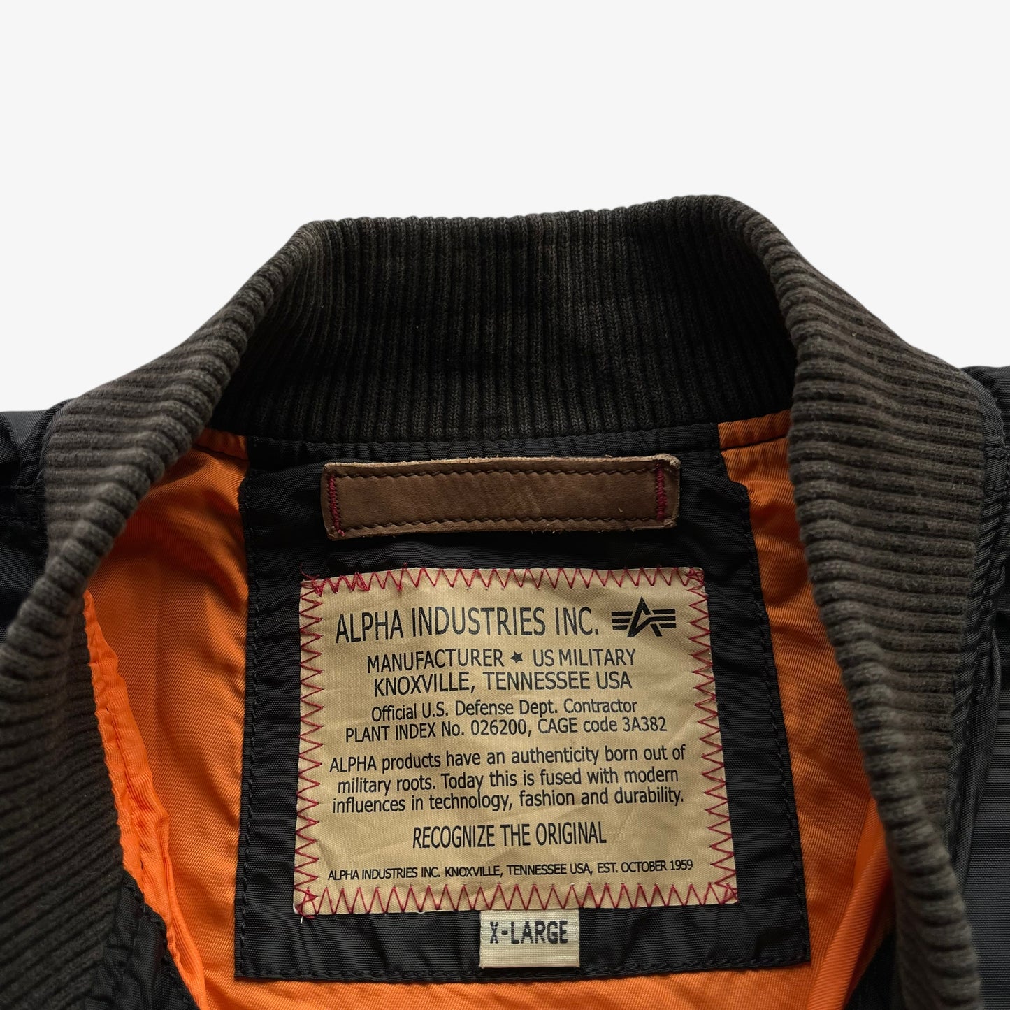 Alpha Industries label stitched inside of men's vintage Y2K black bomber jacket.